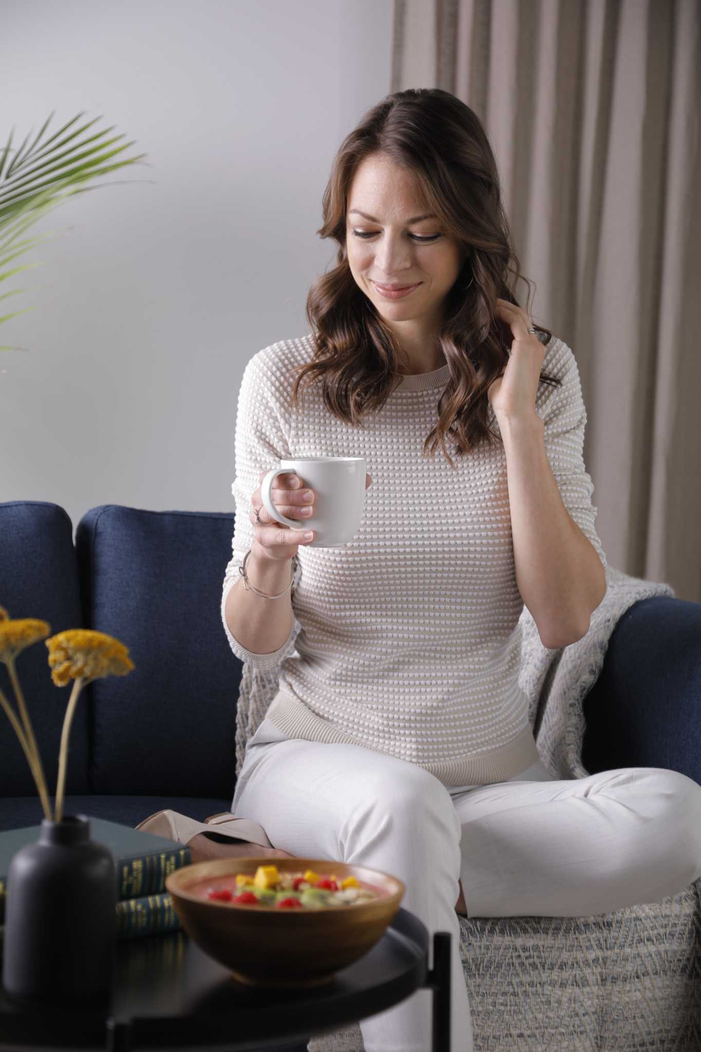 Andréanne Martin profitant d'un moment de détente avec une tasse de café, symbolisant la proximité et l'accompagnement personnalisé qu'elle offre à distance partout dans la francophonie.