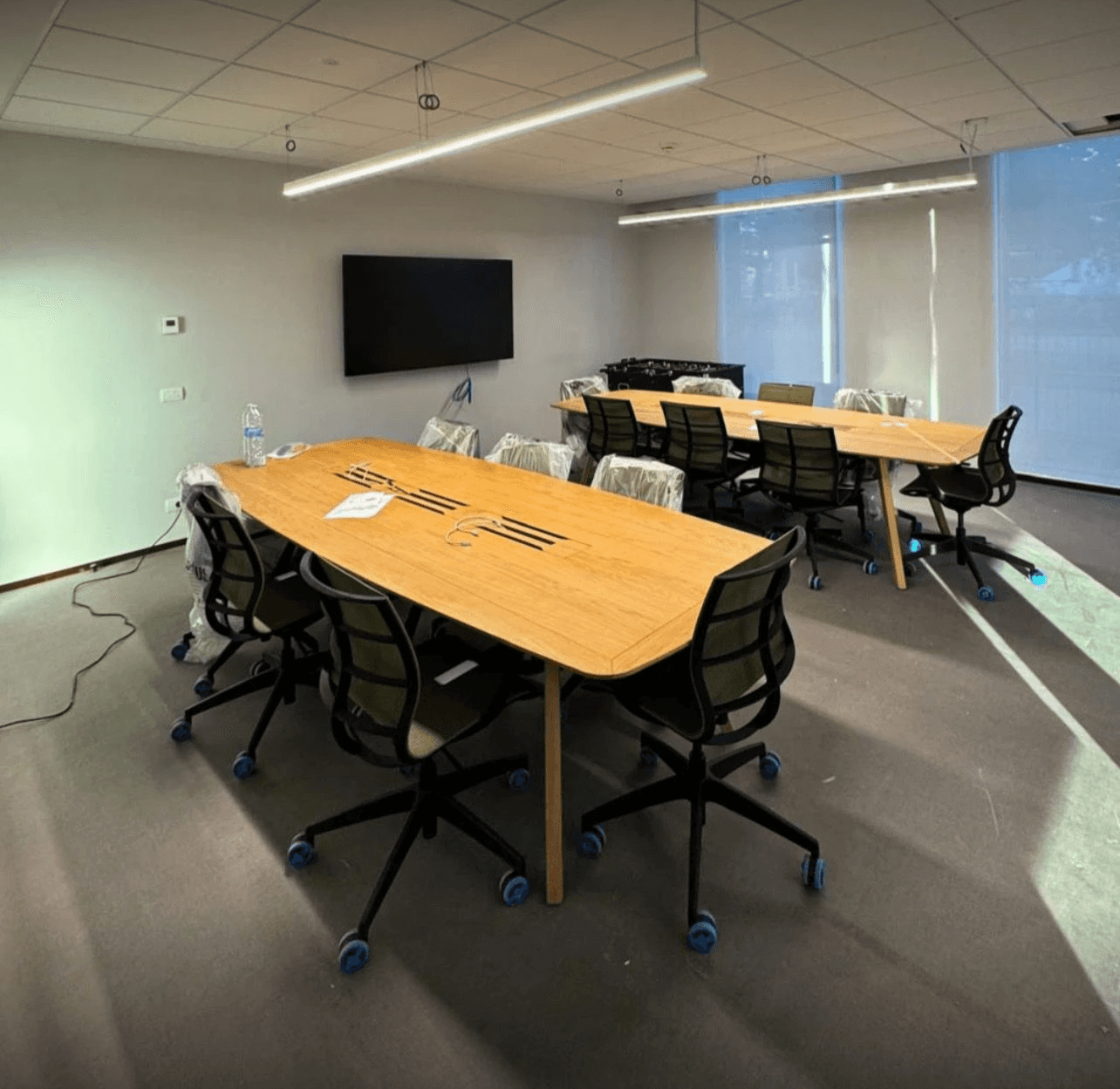 Modern living room with abstract art, beige sectional sofa, indoor plants, and large windows.