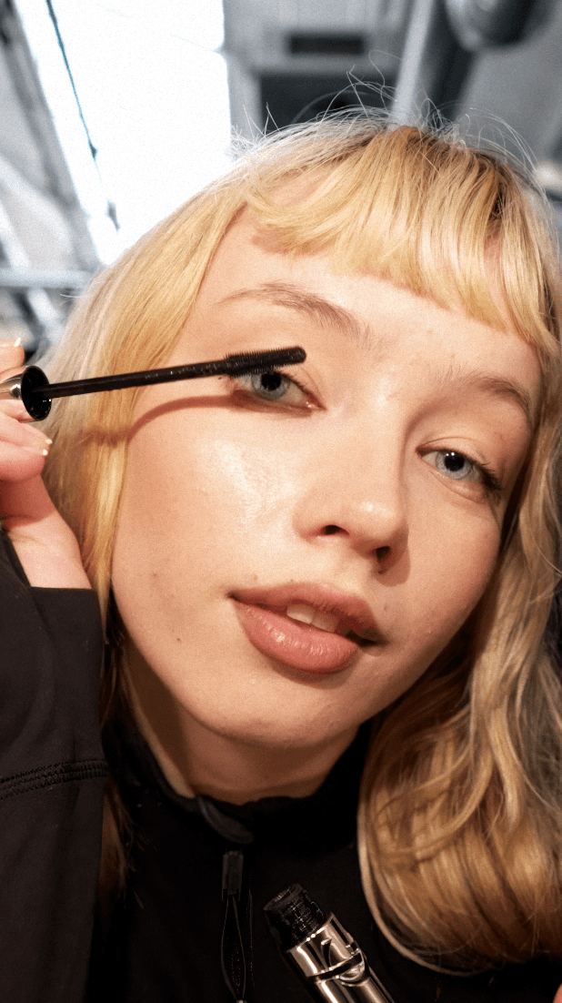 Dancer in black outfit with arms raised, arching backwards