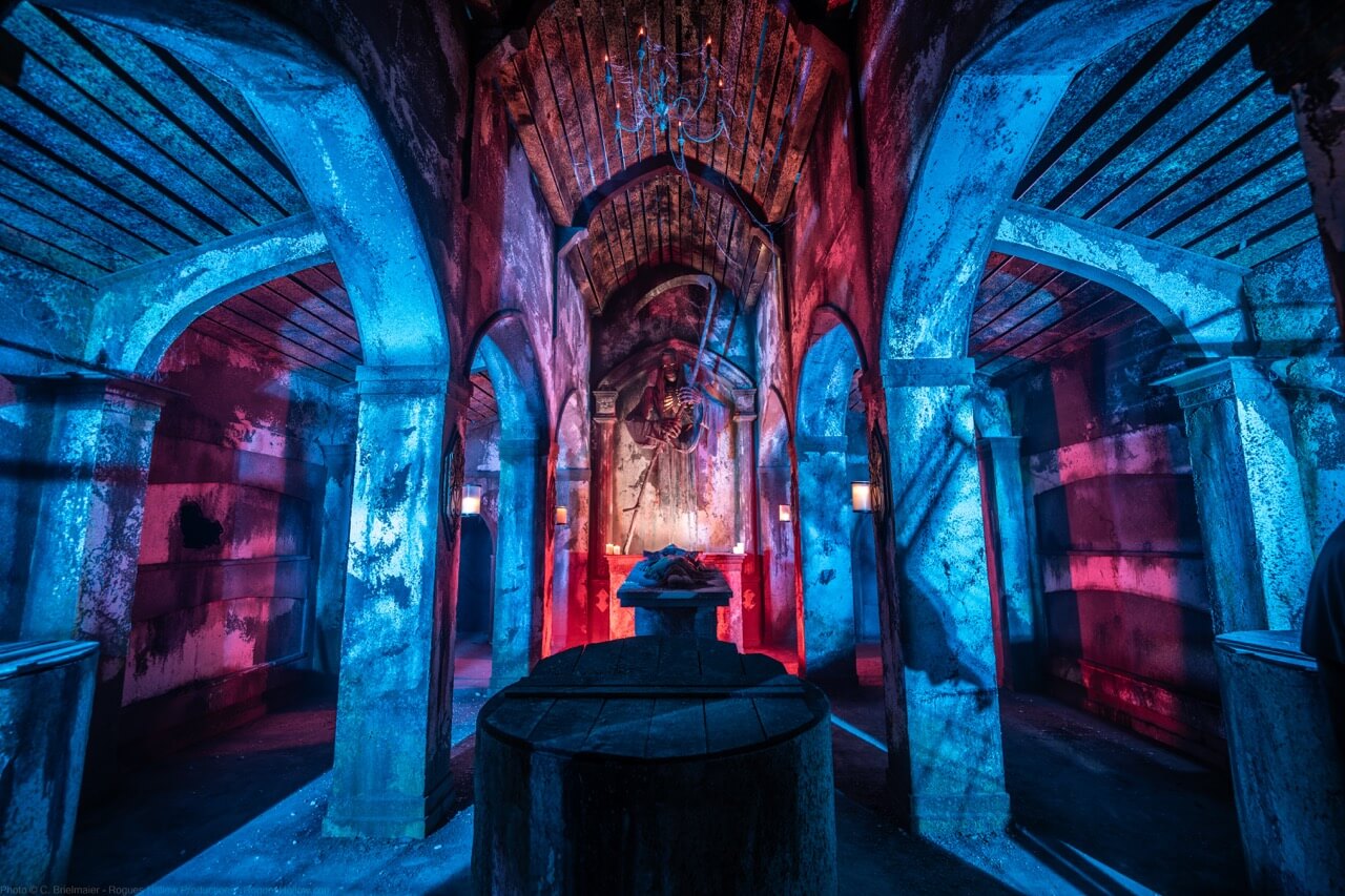 Blue and red-lit crypt room with stone columns and an altar