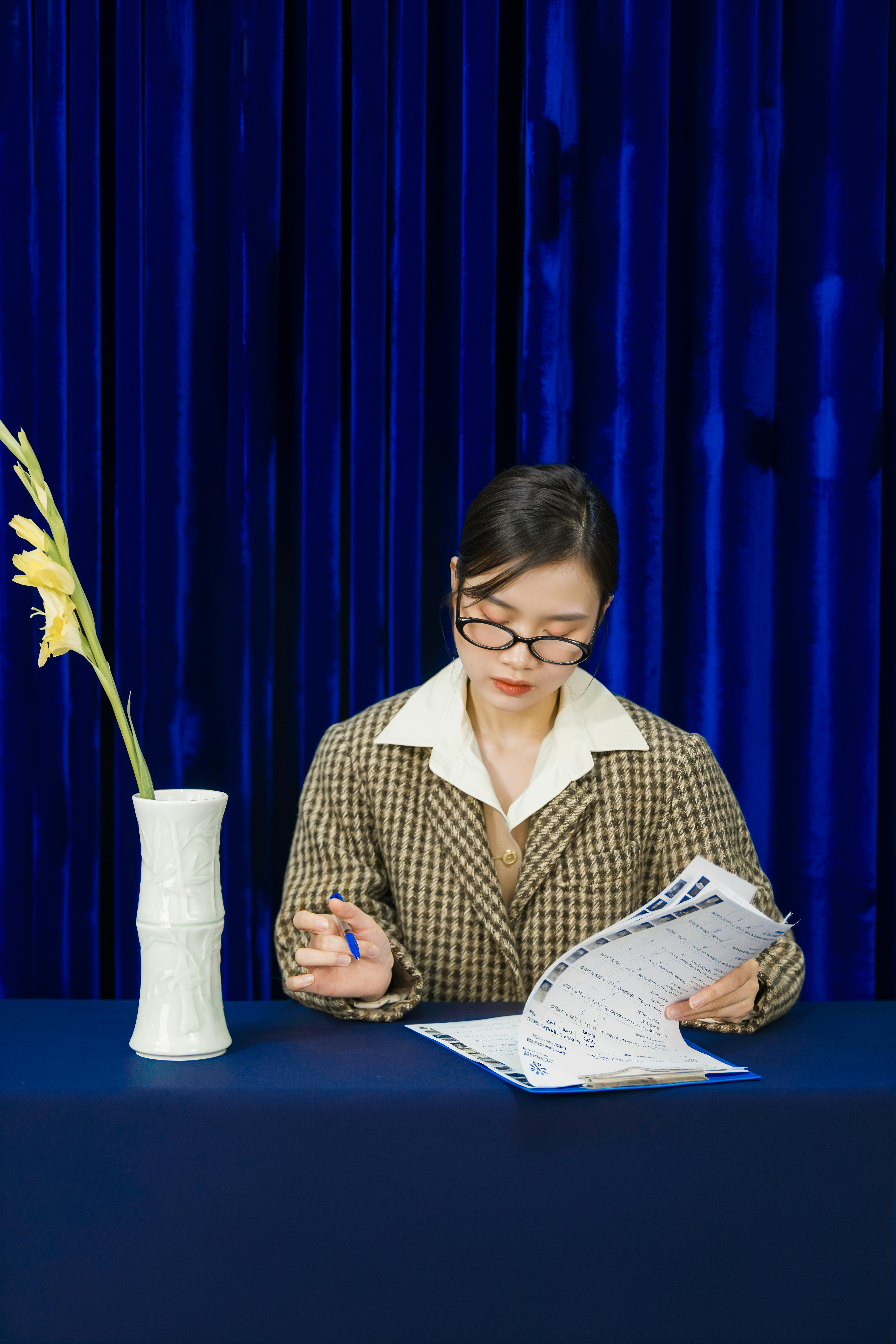 Person reading book at table with vase