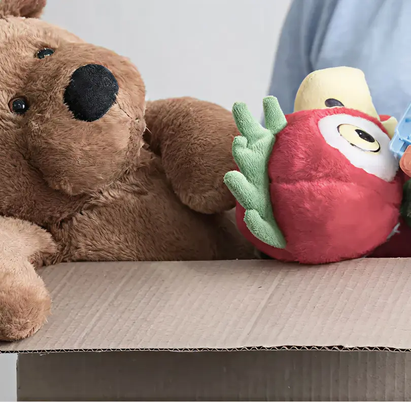 Peluches y juguetes en desuso colocados dentro de una caja de cartón para realizar una donación.