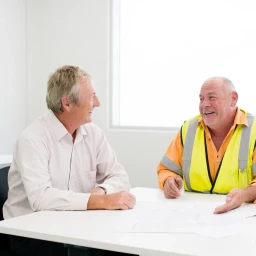 Coordinator and a worker in a high-visibility vest talking over a printed plan