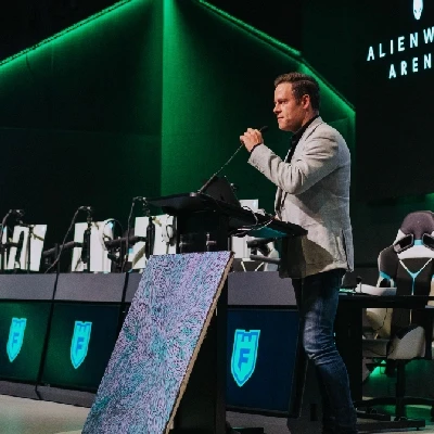 Presenter is on stage giving a speech into a microphone in the Alienware Arena