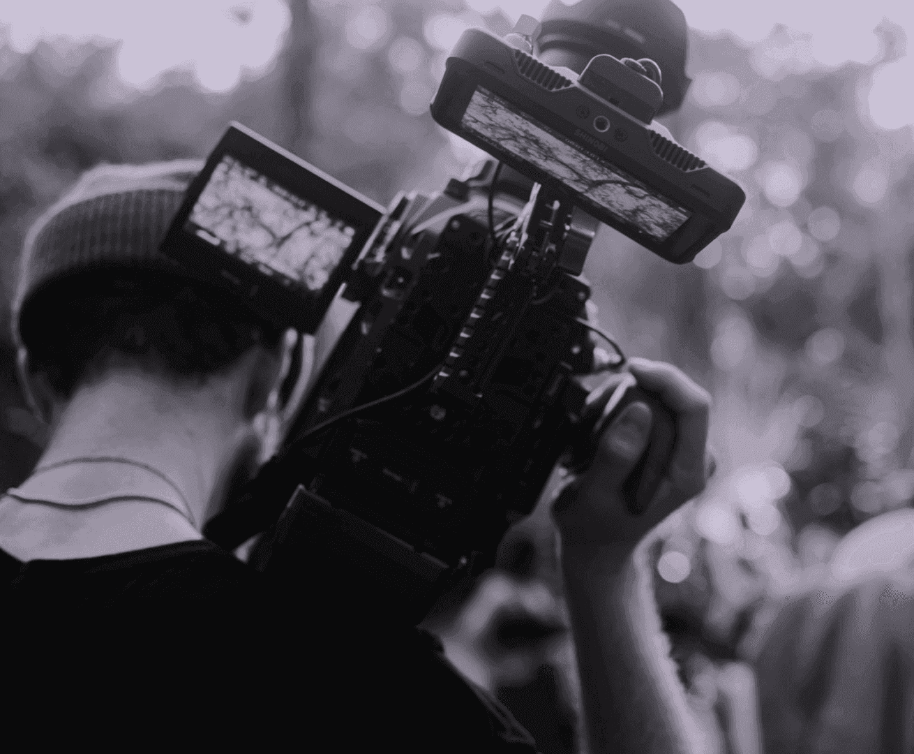 A videographer holds a professional camera on his shoulder at a public event