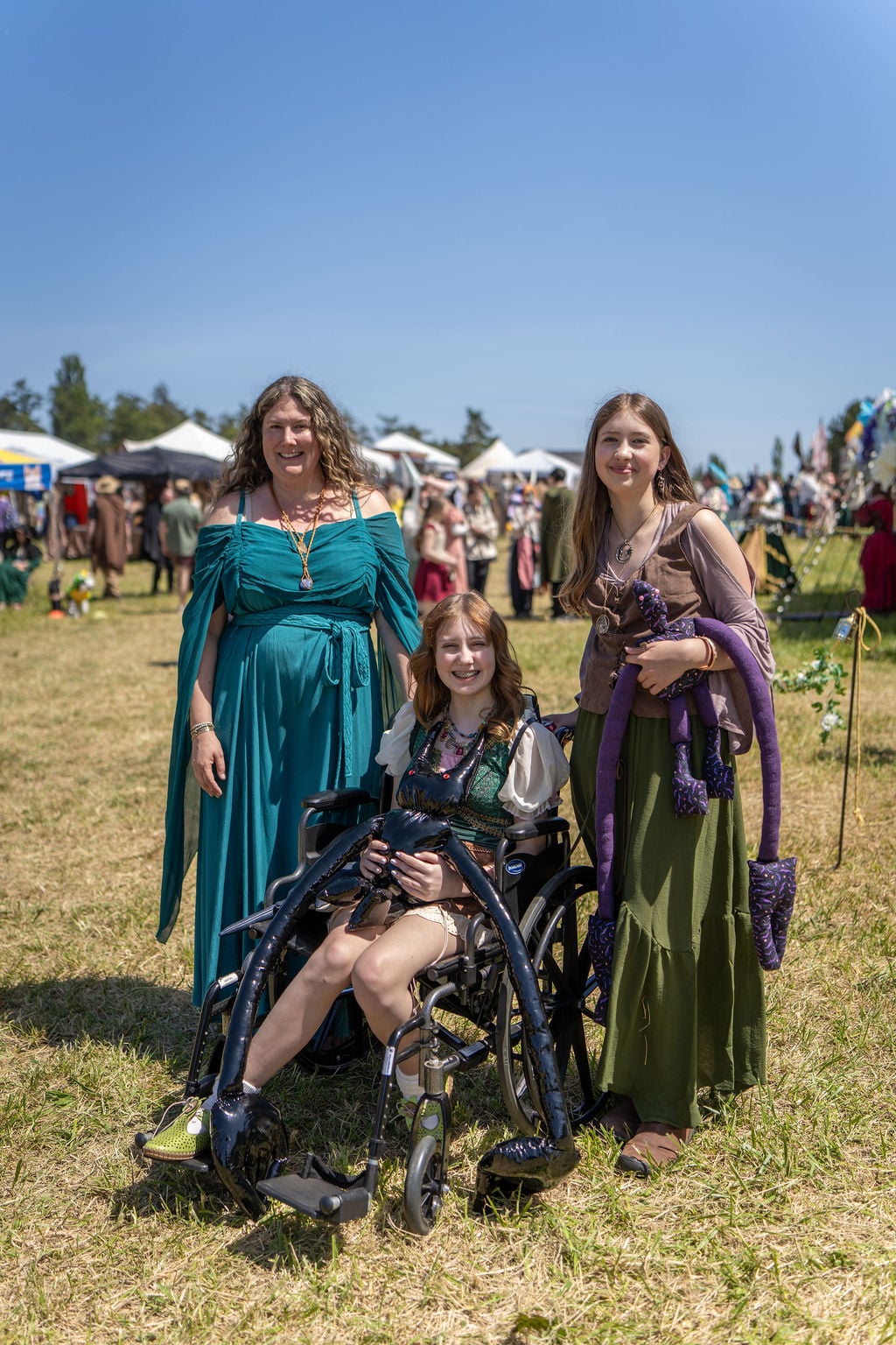 Three faires in costume at whidbey ren faire attendees, one in a wheelchair. By Ted Warner Photography