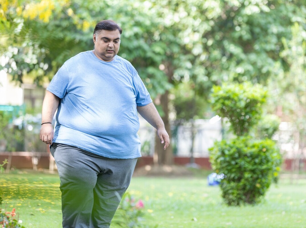 overweight man losing weight by walking outside and keeping a slow pace to match his fitness
