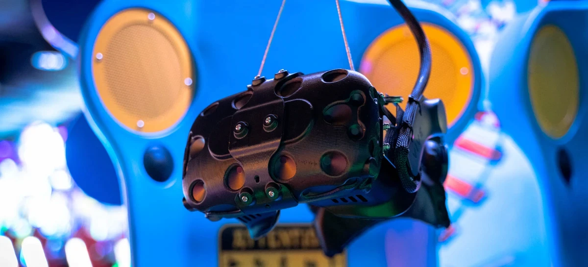 A VR headset hanging ready on a blue and yellow arcade ride