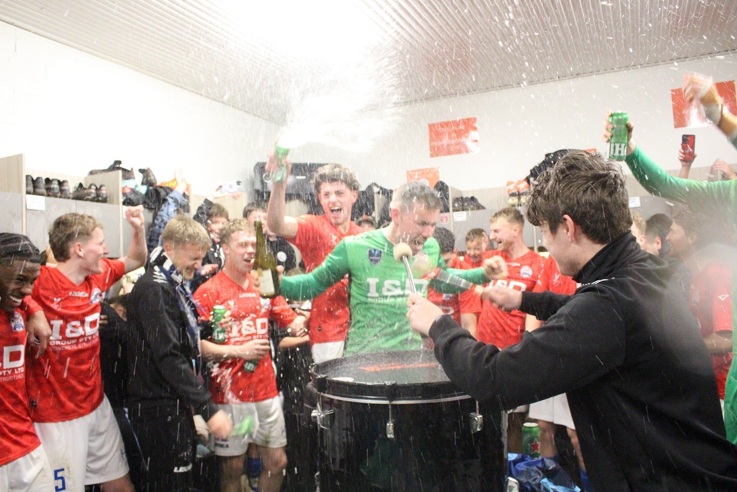 NGWFC senior squad celebrating post-match in changerooms with drinks spraying and team cheering