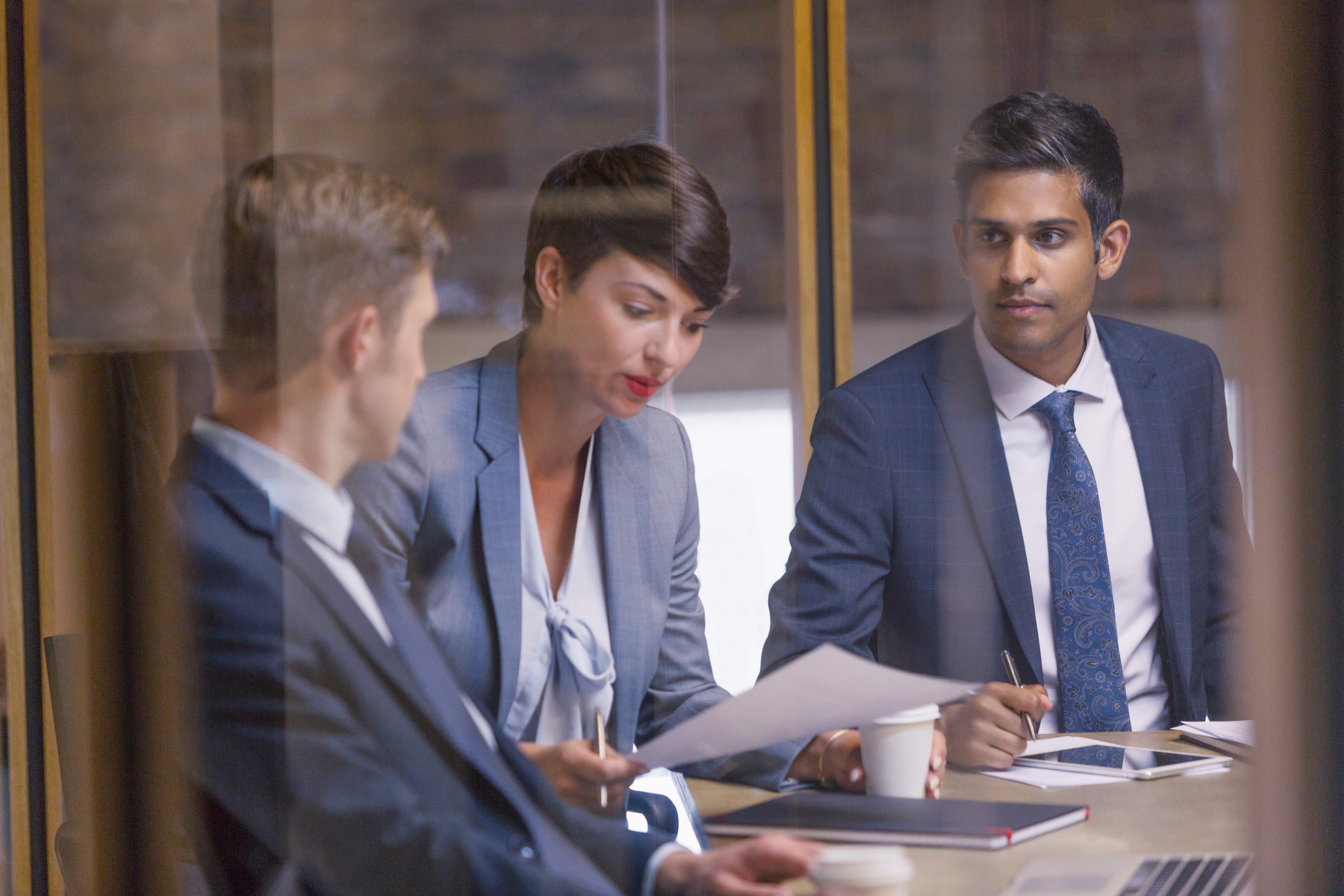 Three professionals in a meeting reviewing documents and discussing decisions in a business setting