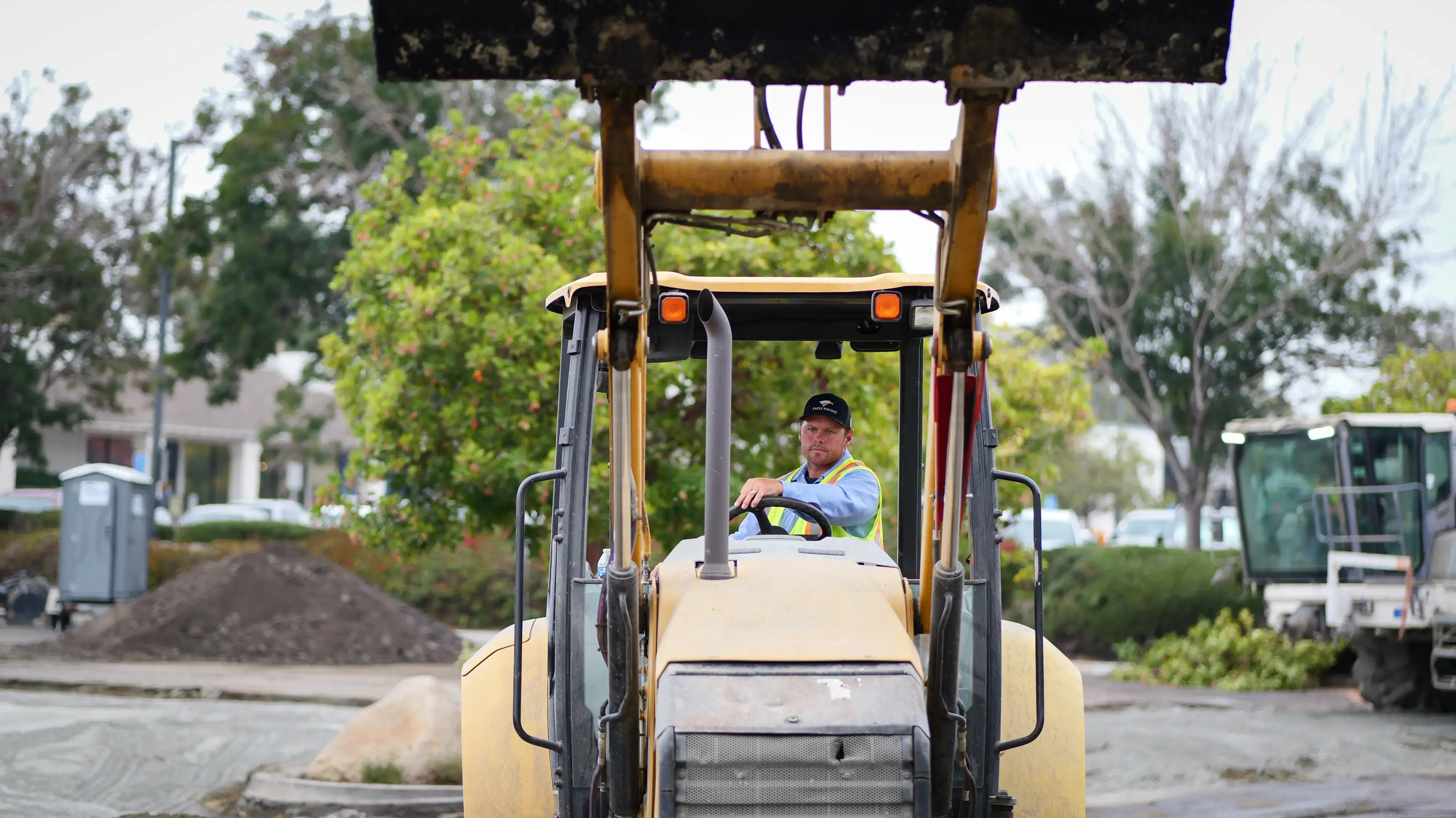 Equipment operator raising bucket scoop on construction site