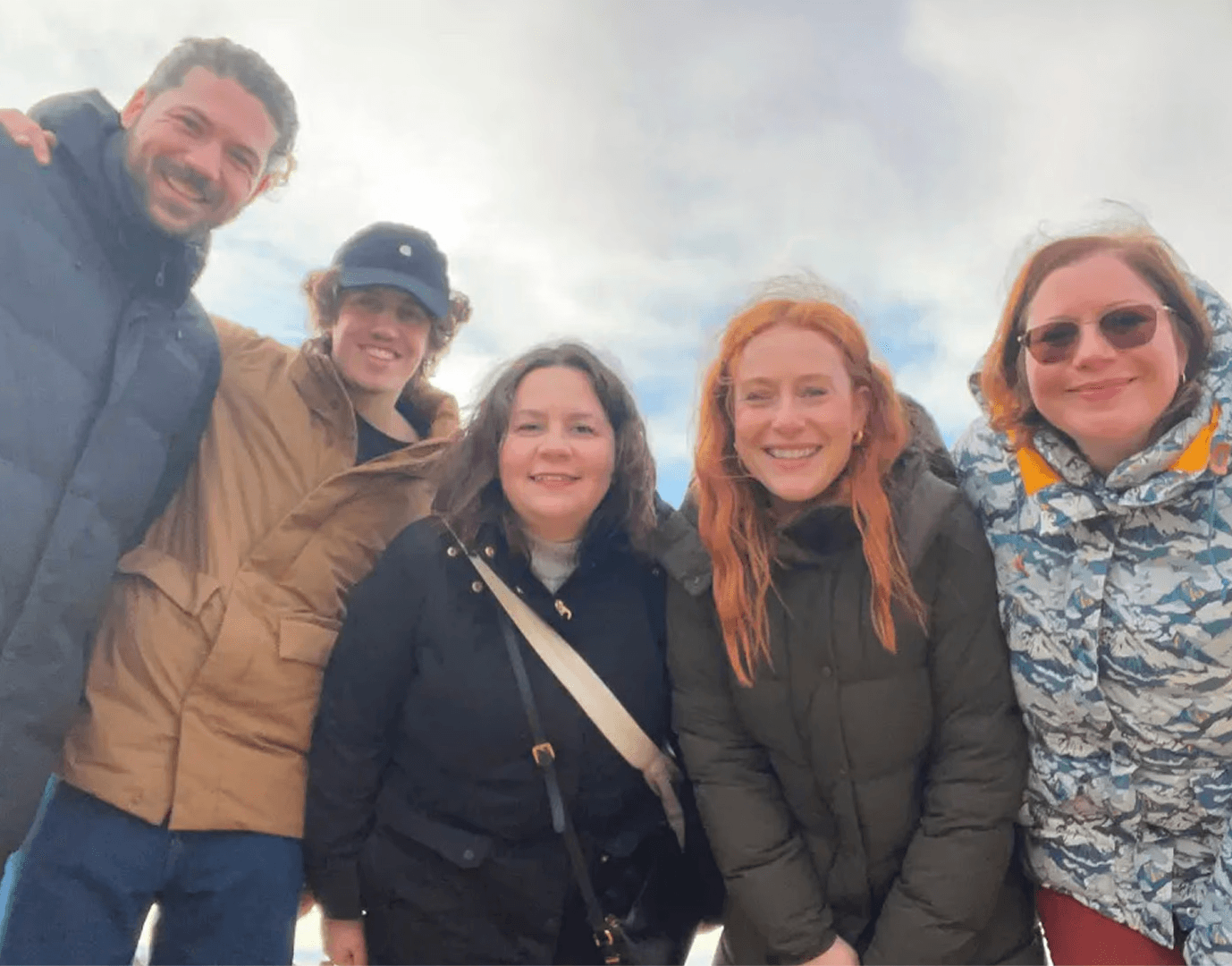 Six Carefree team members smiling in winter jackets standing outdoors under a cloudy sky