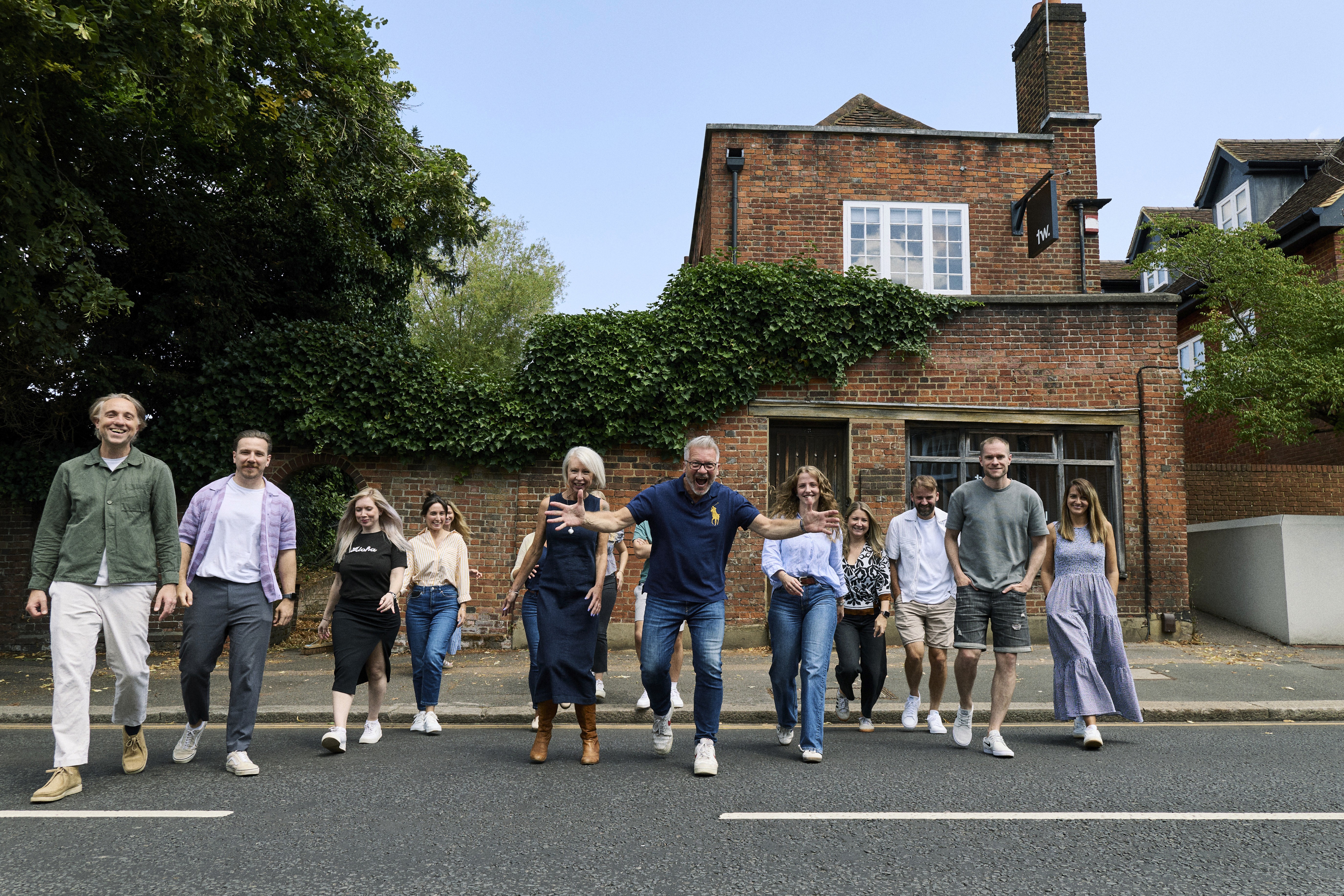 Black and white image of people working at a table with laptops, showing hands gesturing during discussion of digital content displayed on screens, with fabrica® logo in the corner.