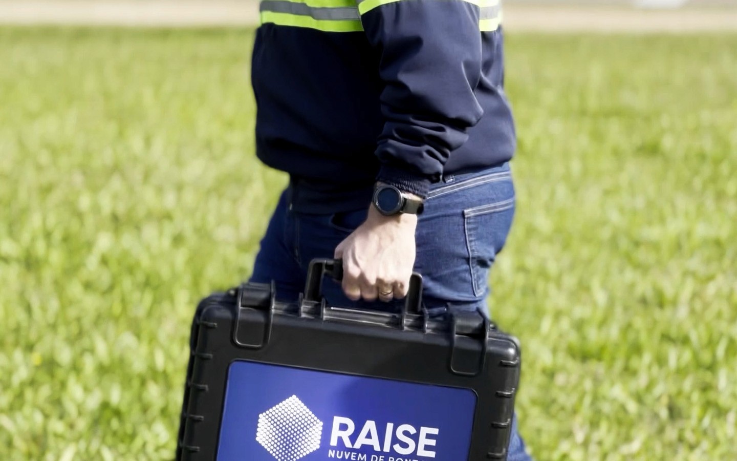 Um profissional em movimento carregando uma maleta técnica rígida com o logotipo 'RAISE - Nuvem de Pontos'. A cena ilustra o início da jornada de Captura da Realidade em campo, onde equipamentos de alta precisão são transportados para realizar o escaneamento do ambiente.