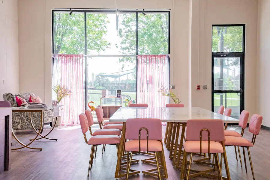 The Soulfully Wild studio with a long table, soft pink chairs, and tall windows.