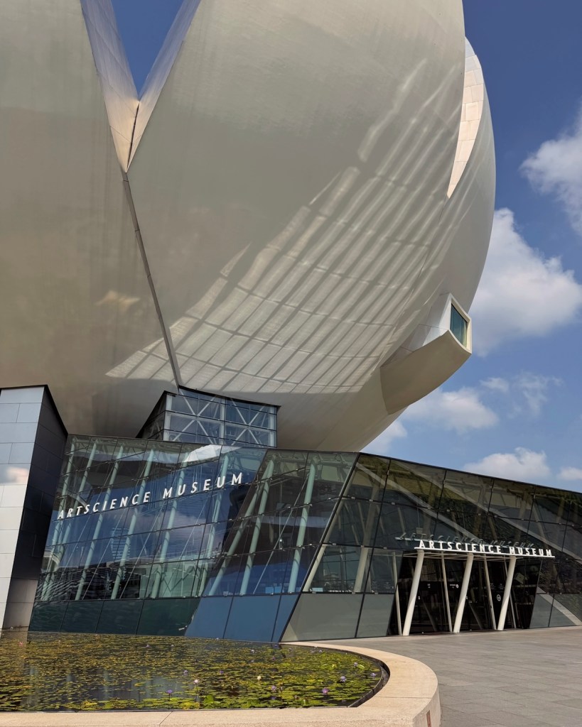 The exterior of the ArtScience Museum featuring a modern design with a unique lotus-like structure, surrounded by a pond.