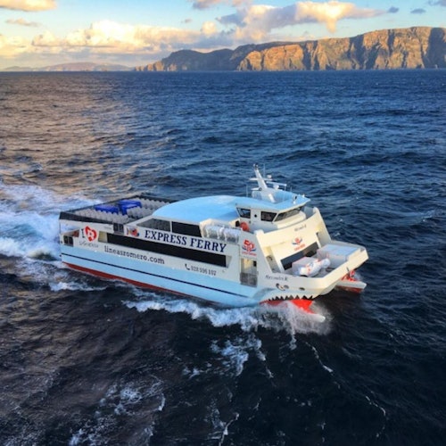 A white and red ferry labeled "Express Ferry" travels over a blue ocean, with a rocky cliff coastline in the background.