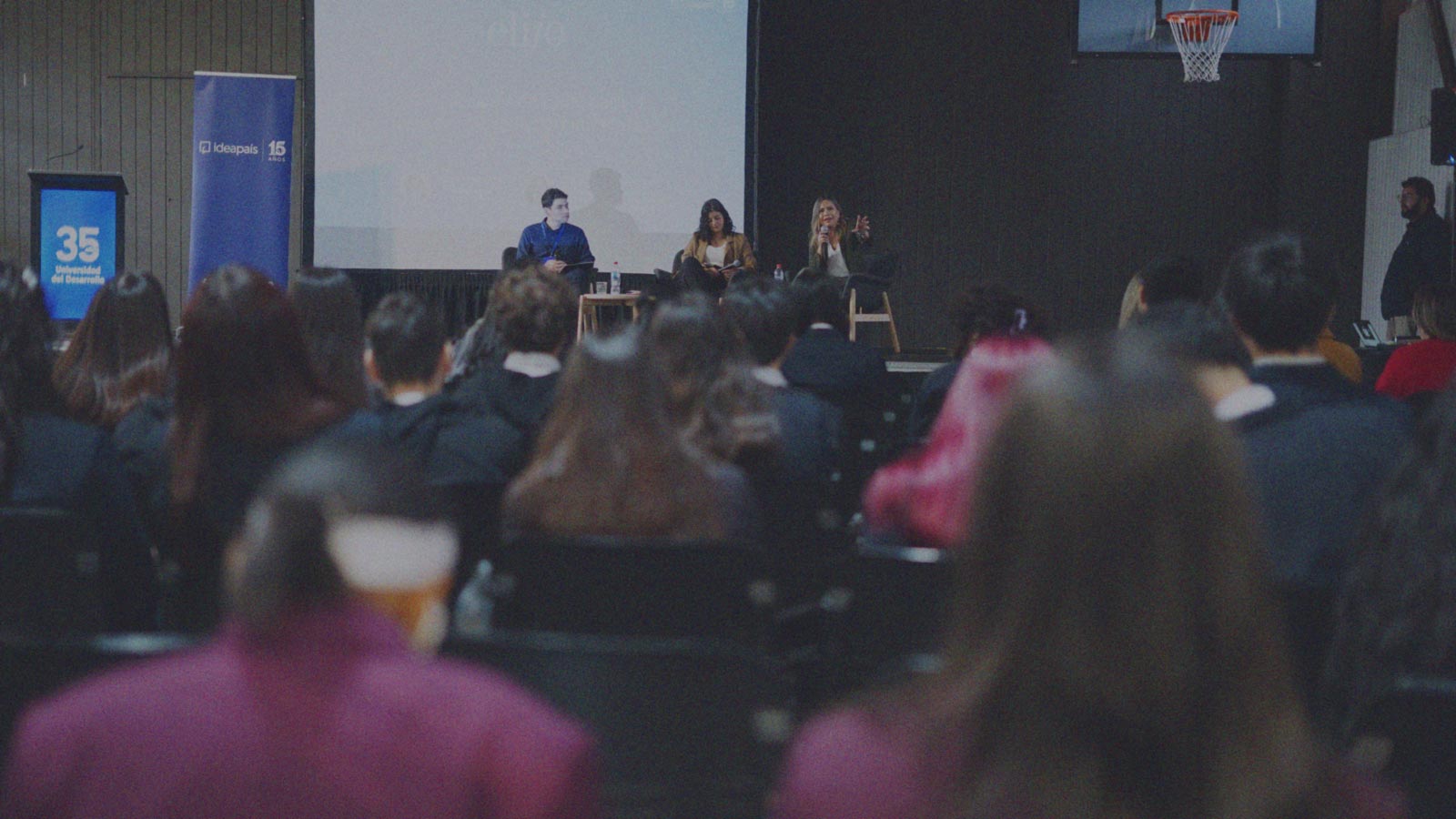 Foto de tres personas en una tarima hablando a jóvenes que participaron del Encuentro de Líderes Jóvenes (ELIJO) en la Región del Biobío. 