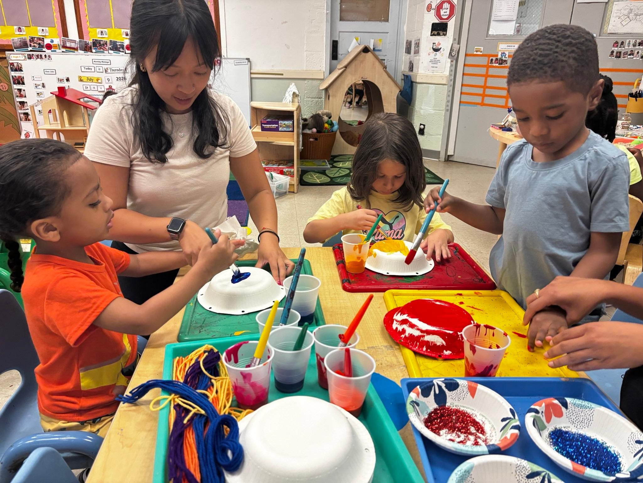 Teacher joins in painting paper bowls to make jellyfish.