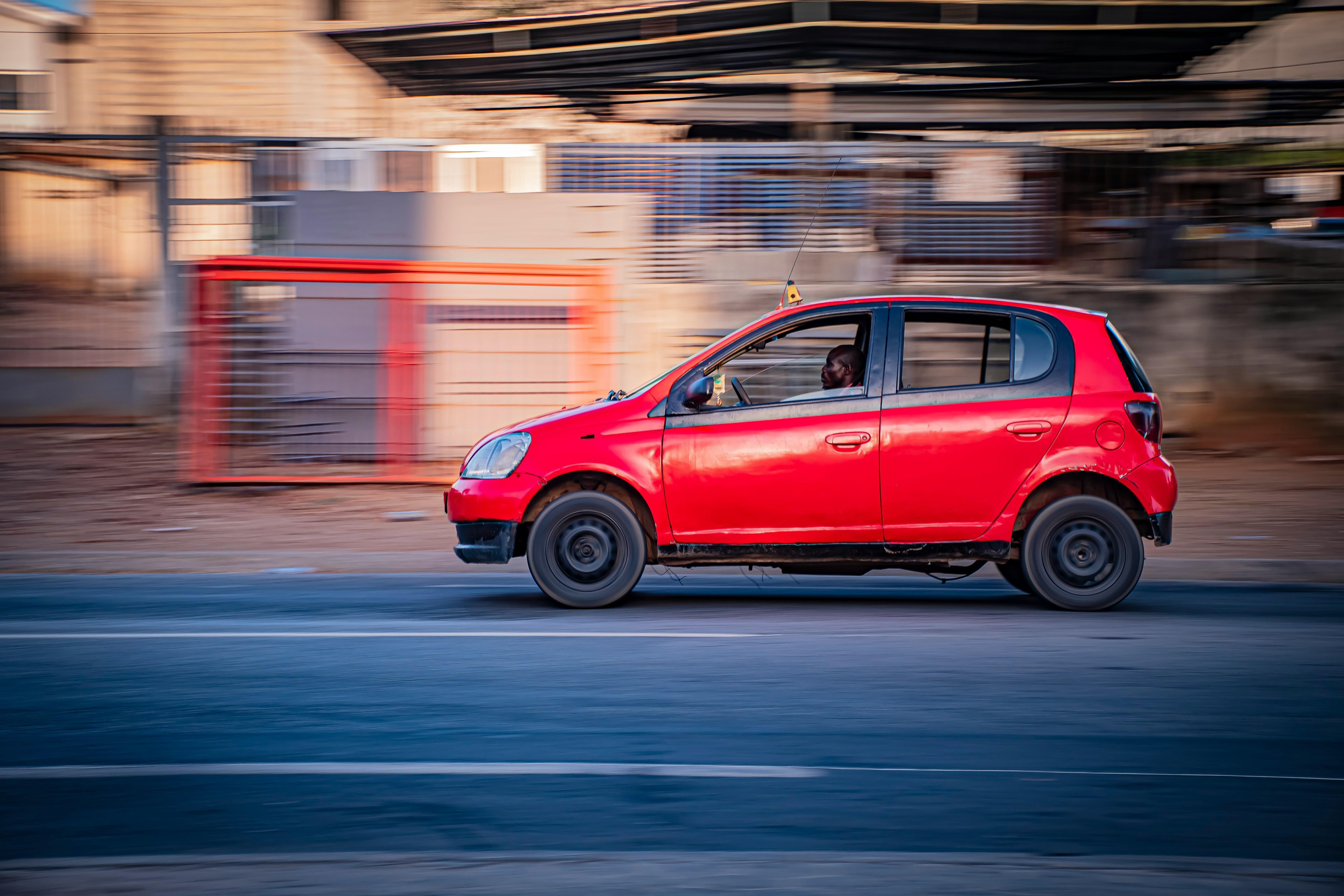 A red car driving on a road with motion blur