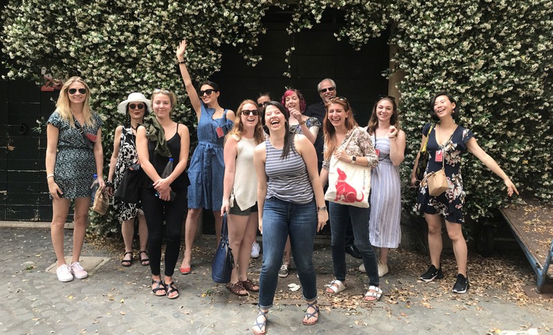 A photo of a group of people standing near a hedge.