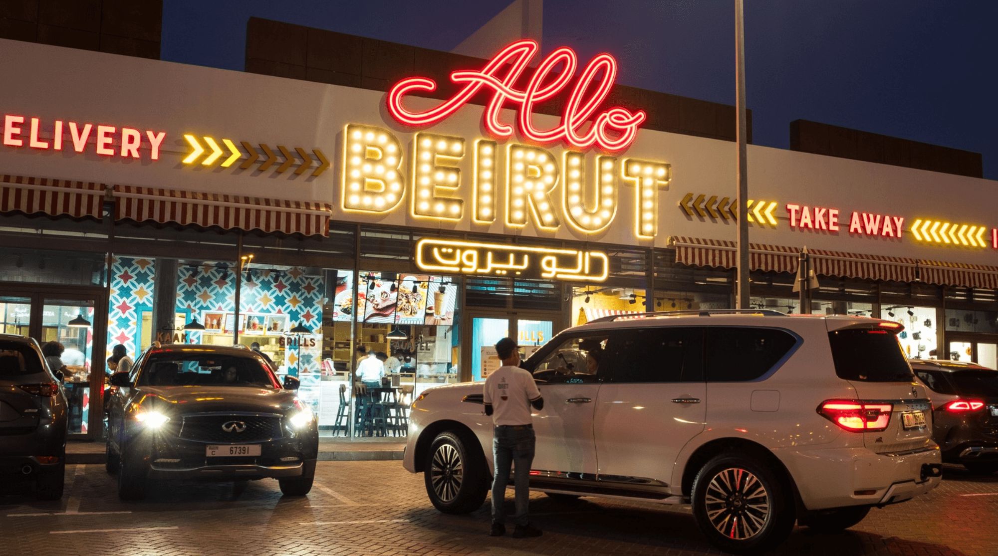 Allo Beirut in Dubai with bright, neon signage and parked cars.