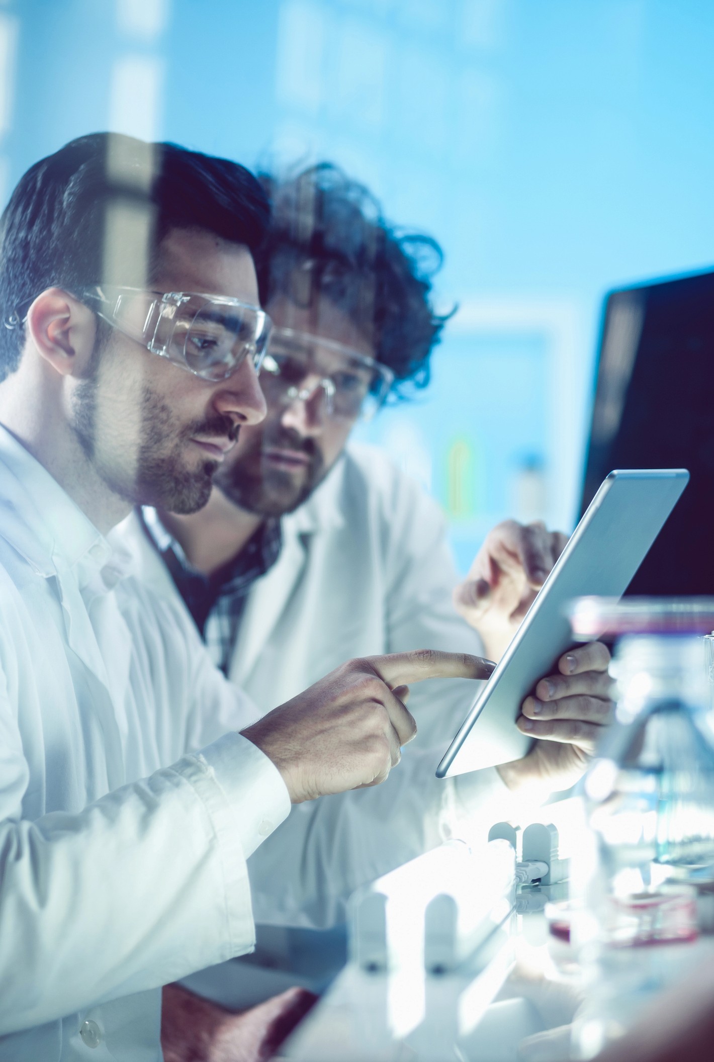 Female scientist wearing a white coat and gloves examines a sample slide in a modern laboratory setting.