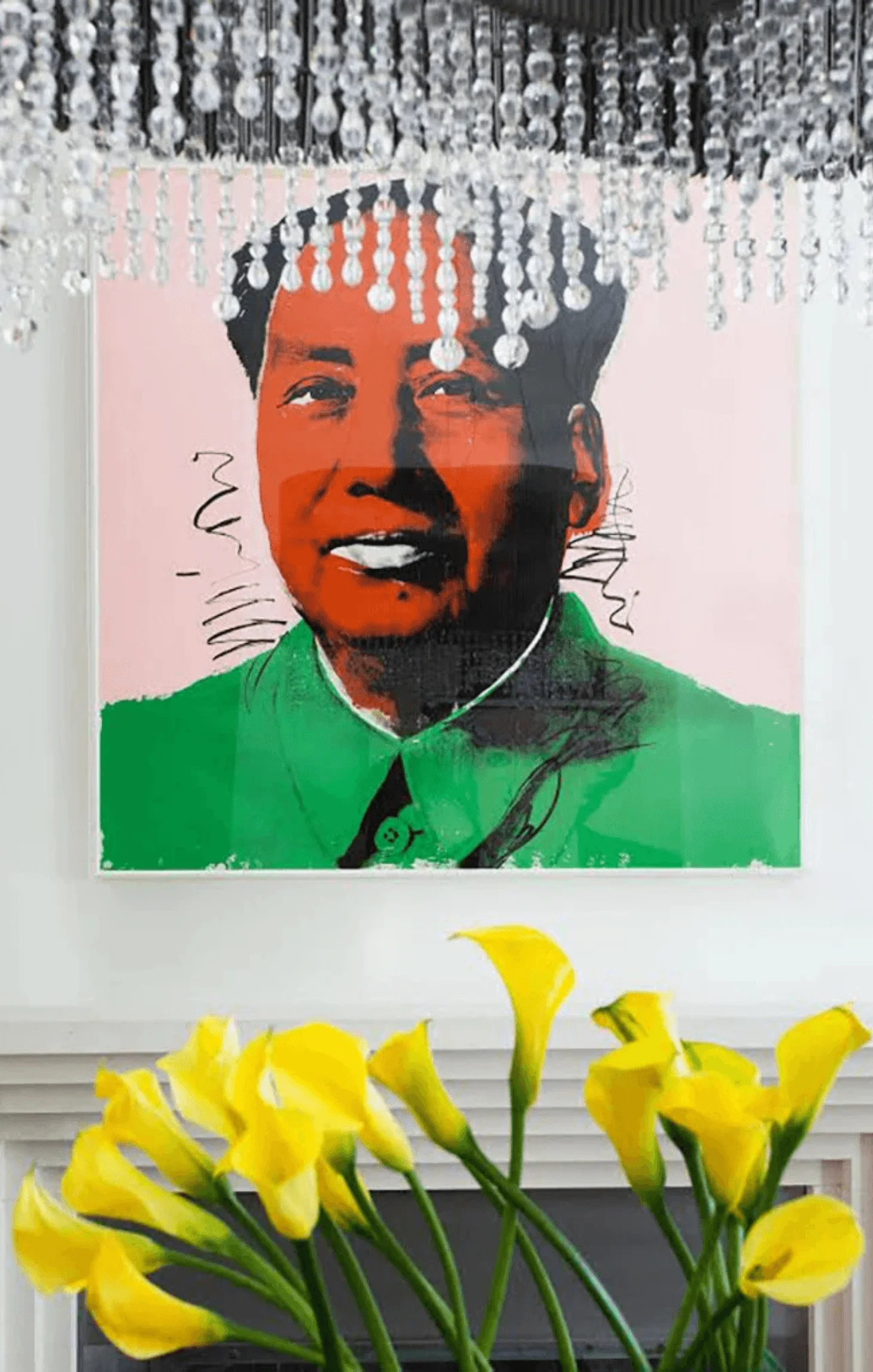 Andy Warhol's Mao portrait hangs above the fireplace, framed by a crystal chandelier and yellow calla lilies
