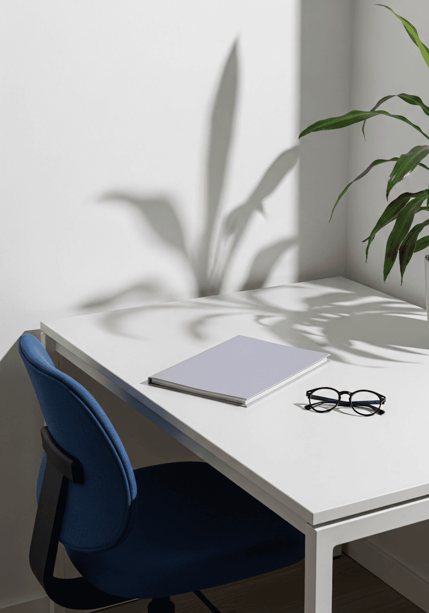 A desk with a notebook and glasses beside a plant