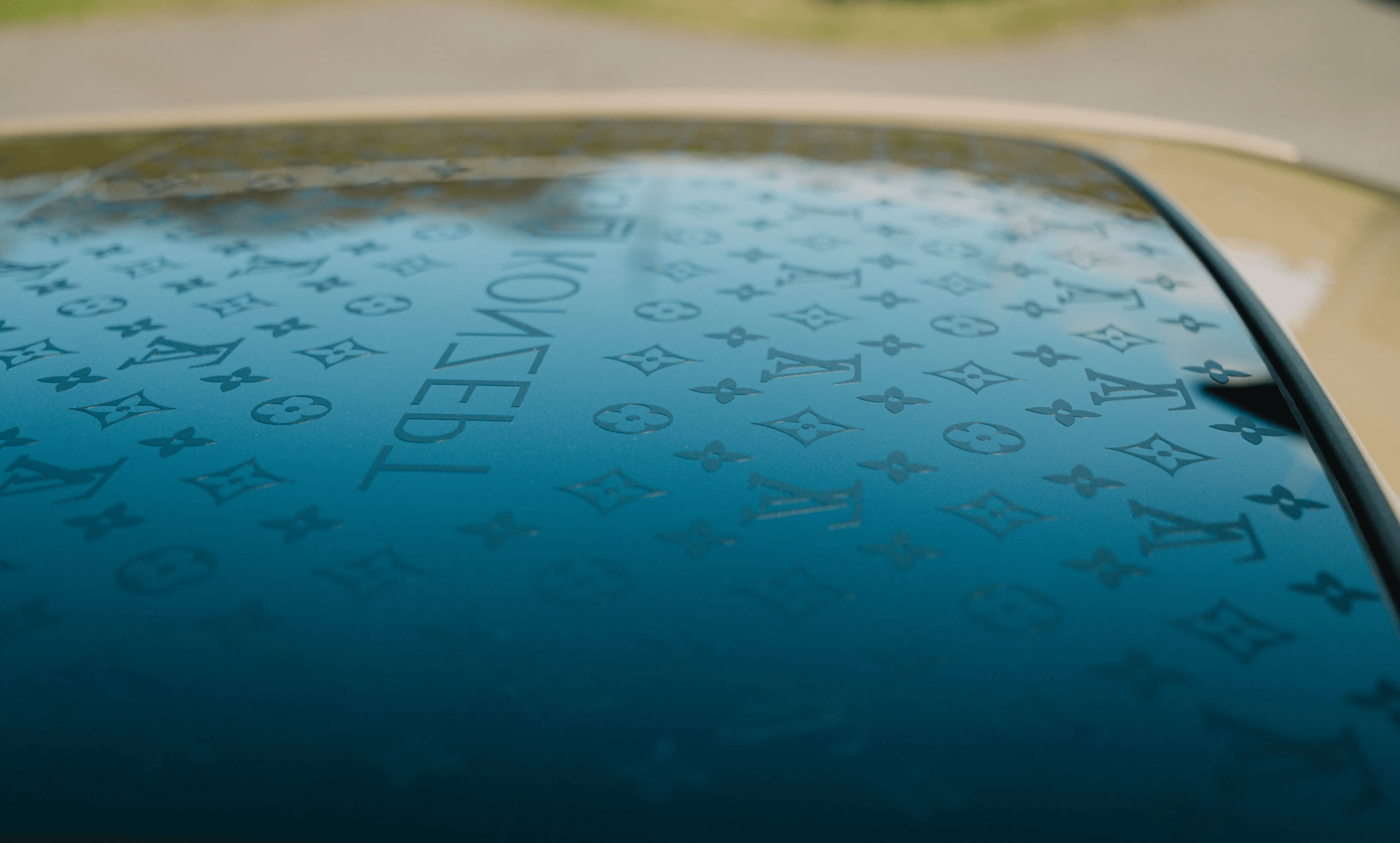 Detailaufnahme des Panoramadachs eines Audi Q8 mit einem dezenten, integrierten LV-Monogramm-Muster in der Tönungsfolie.