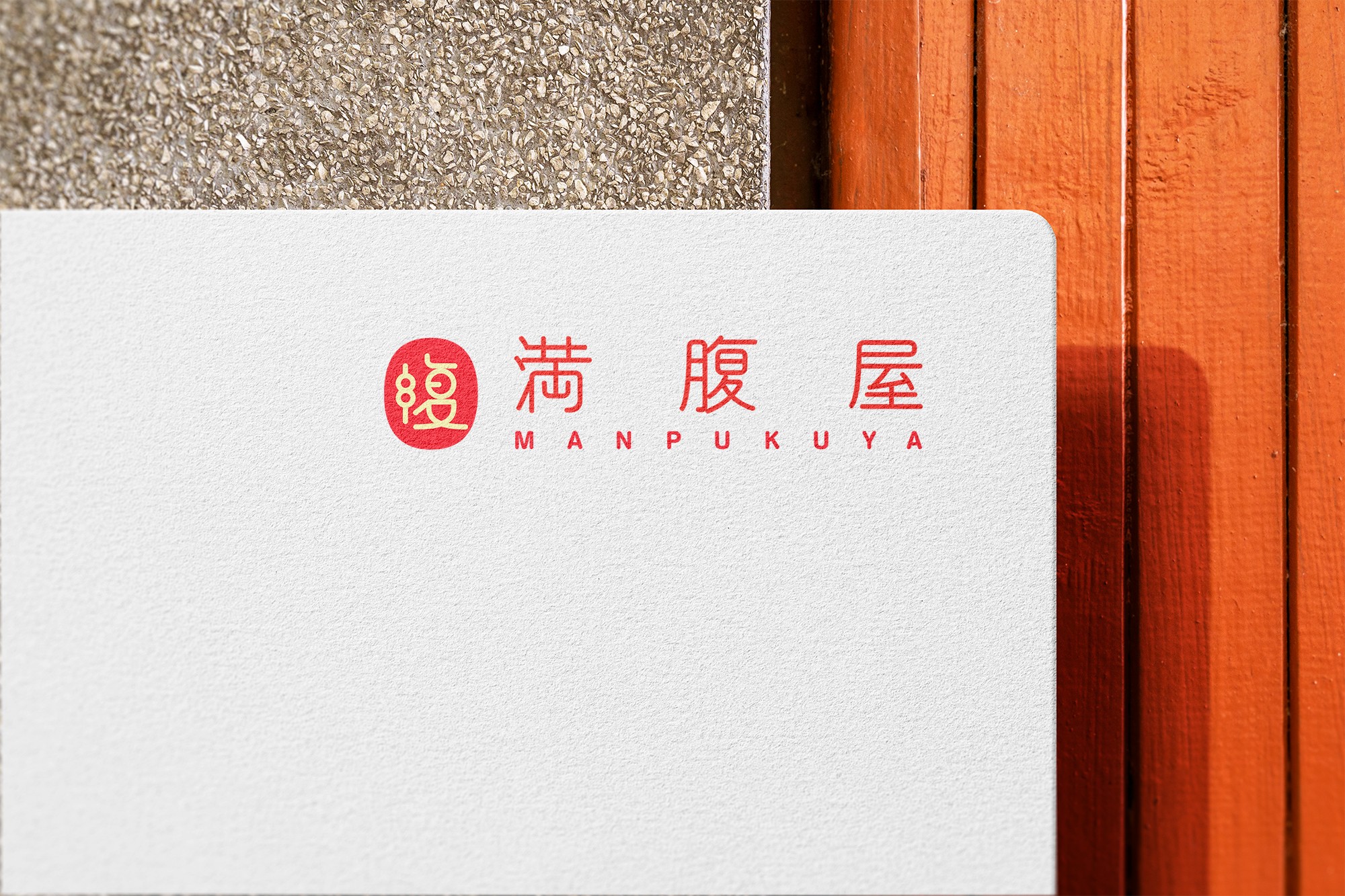 這張圖片展示了滿腹屋的品牌標識,紅色的中文字體「滿腹屋」和英文字體「MANPUKUYA」印在白色背景上,標識左側有一個紅色圓形圖案,圖內有一個「腹」字。