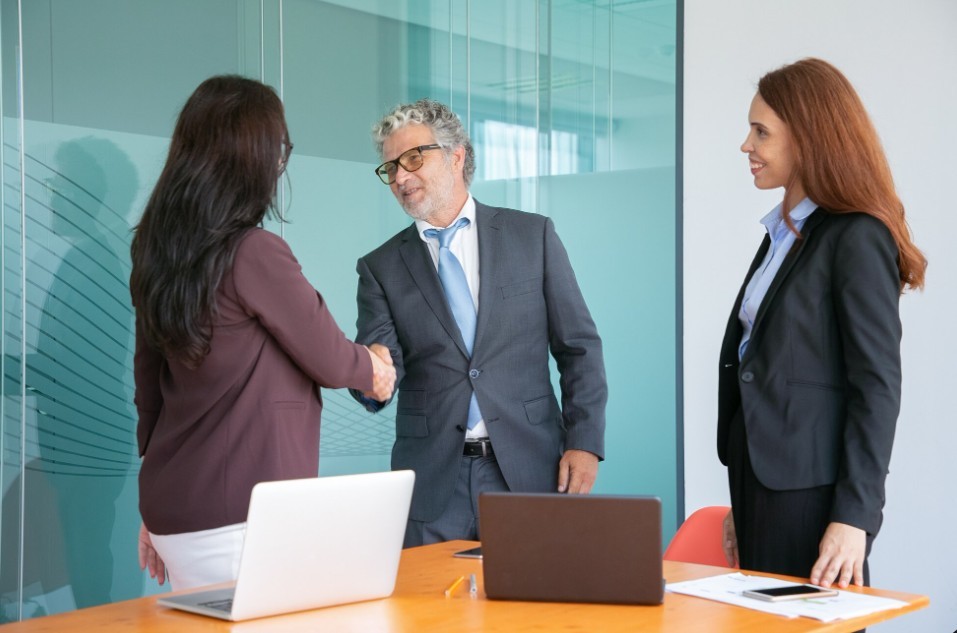 Business professionals shaking hands in a modern office to appoint an approved agent for JAFZA offshore company registration.