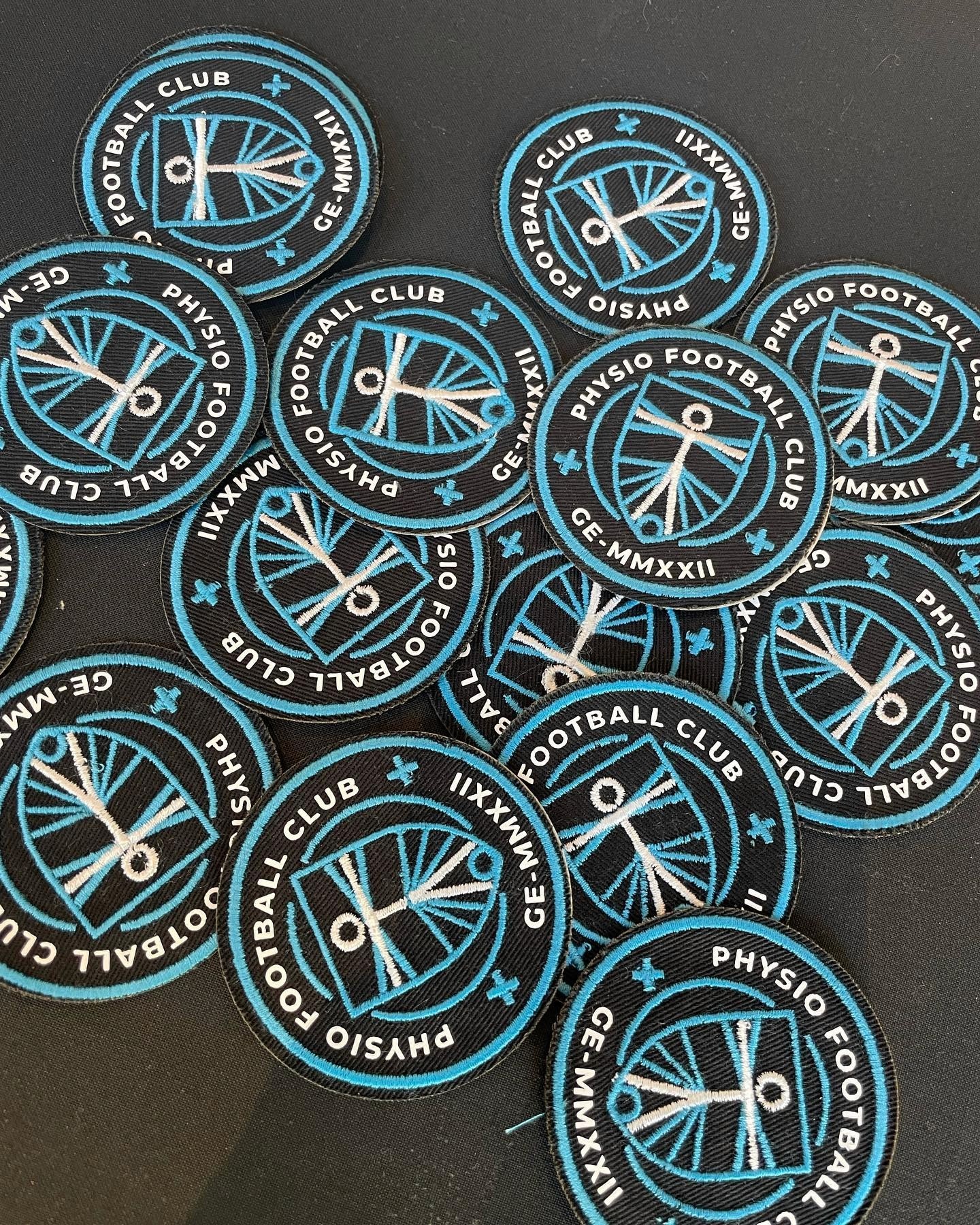 A smiling young man with crossed arms, wearing a plaid shirt and white t-shirt, poses against a dark background.