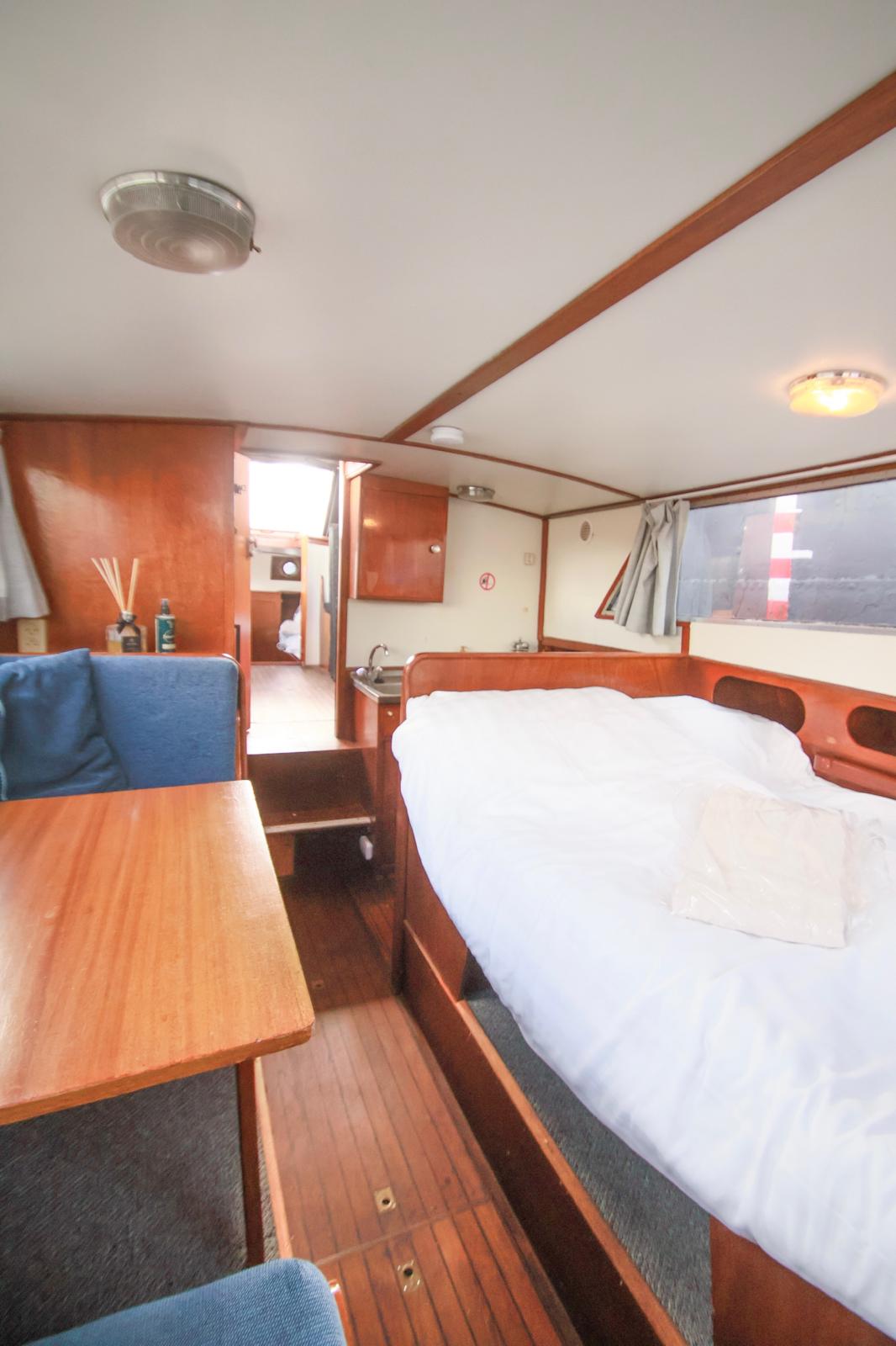 Beige upholstered bed with patterned pillows and ottomans
