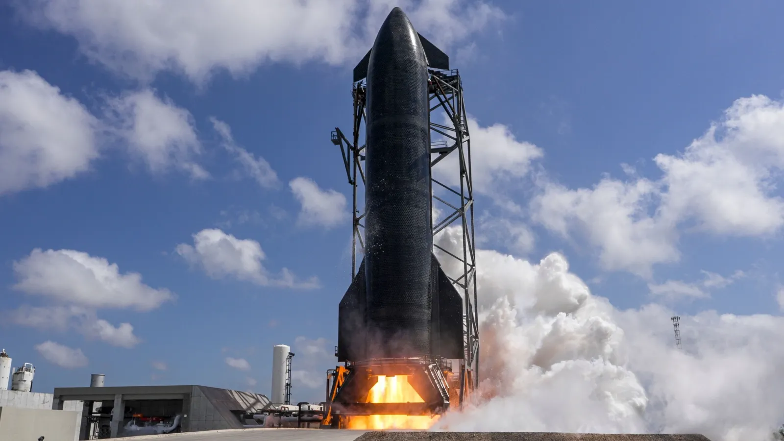 A rocket lifts off from a launch pad against a backdrop of a partly cloudy sky, with flames and smoke visibly erupting from its engines.