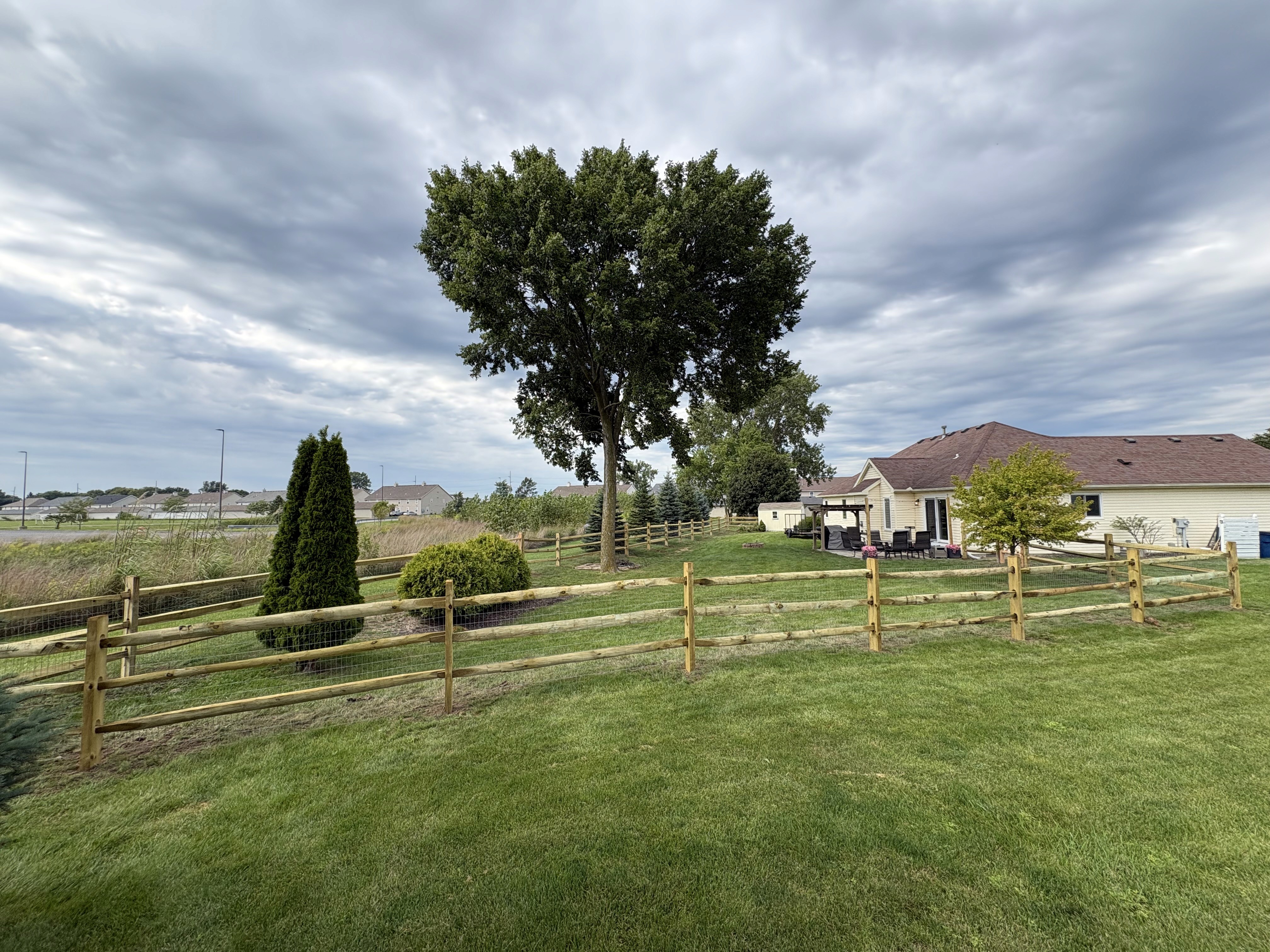 Additional view of the completed wood split-rail fence and residential lawn
