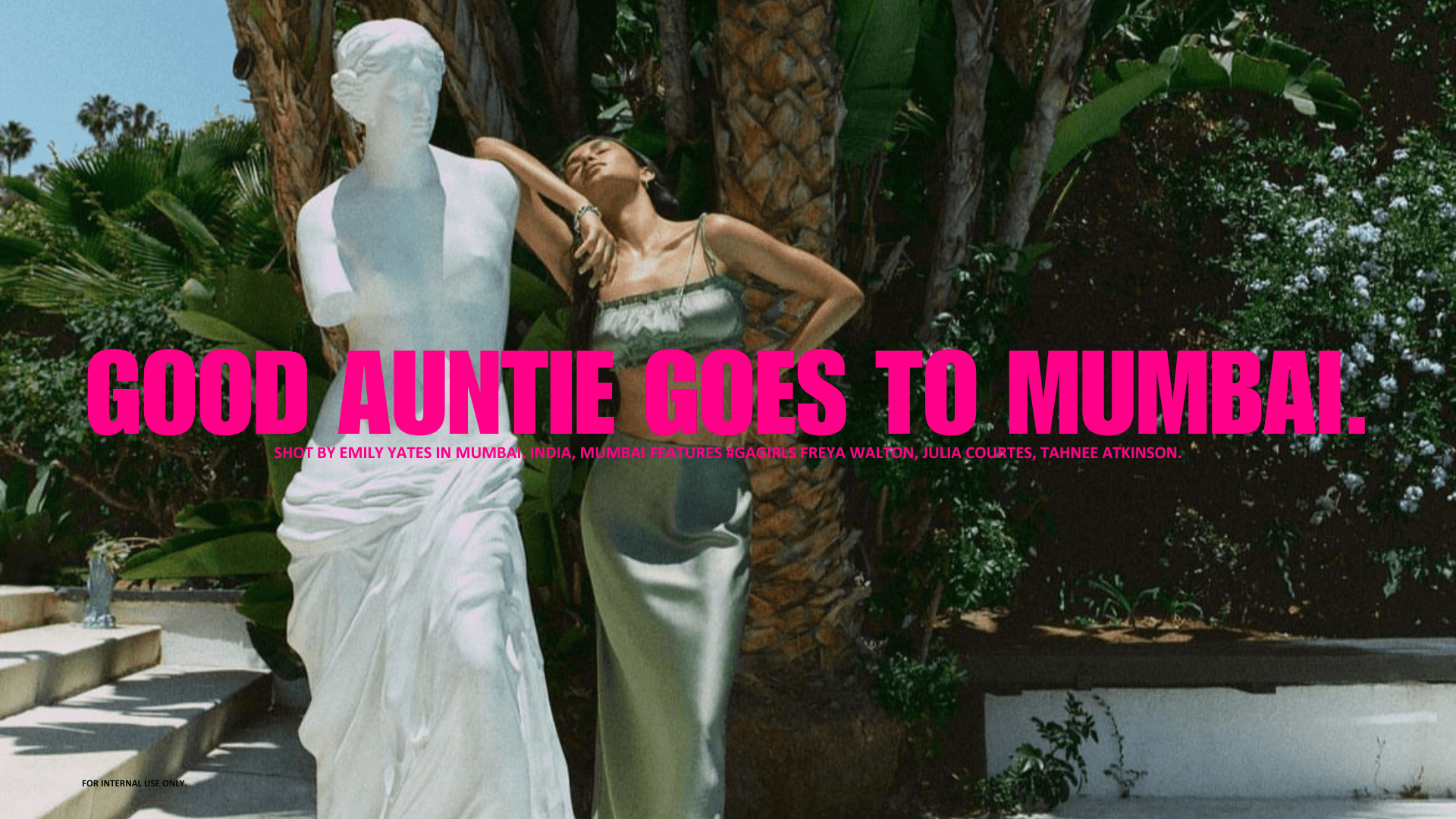 Promotional image with the headline “Good Auntie Goes to Mumbai,” showing a woman posing beside a classical statue in a lush outdoor setting.
