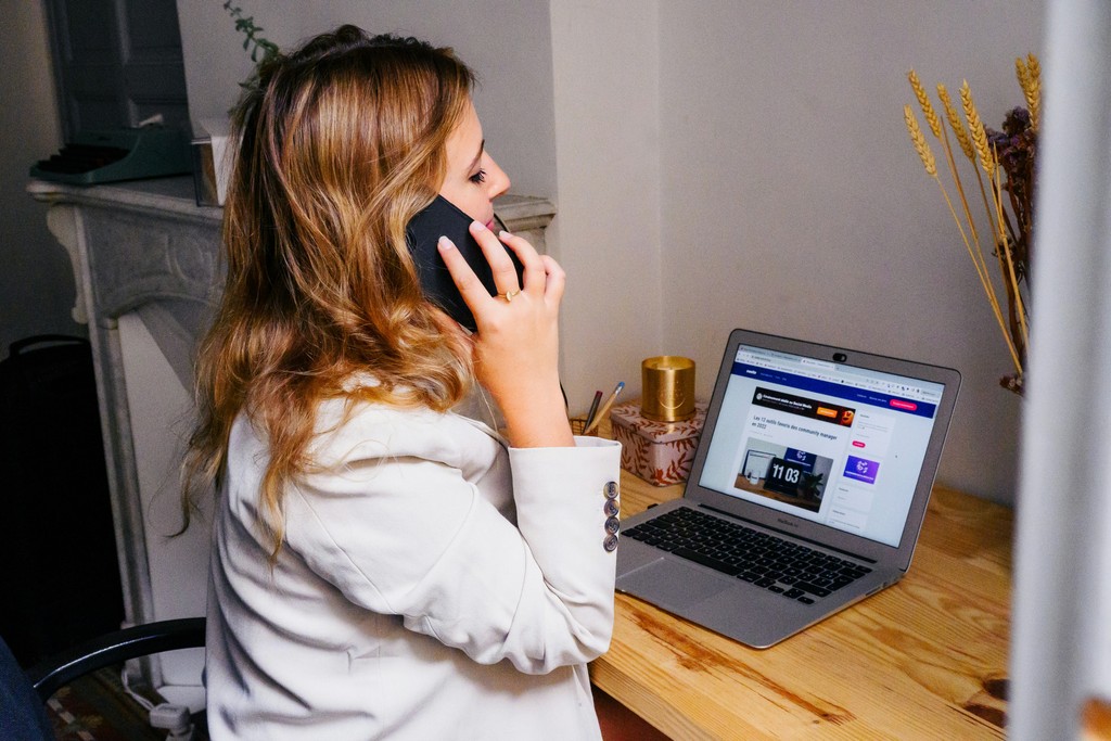 a woman sitting at a desk with a laptop and a phone