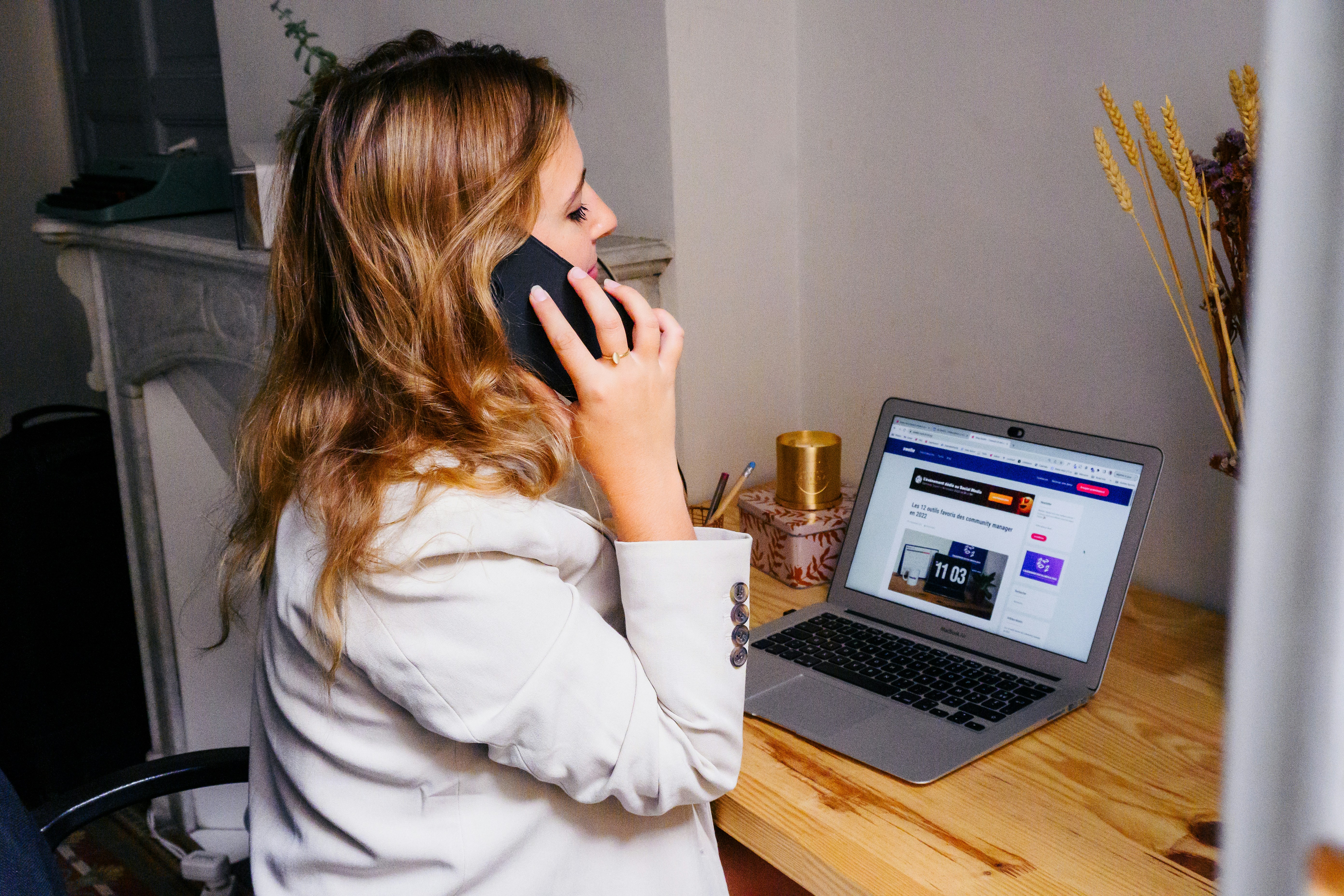 a woman sitting at a desk with a laptop and a phone