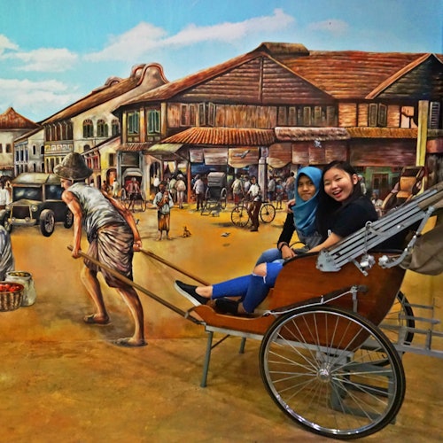 两位女士坐在一辆人力车上,背景是热闹的历史街景壁画,展现了建筑物和人群的场景。