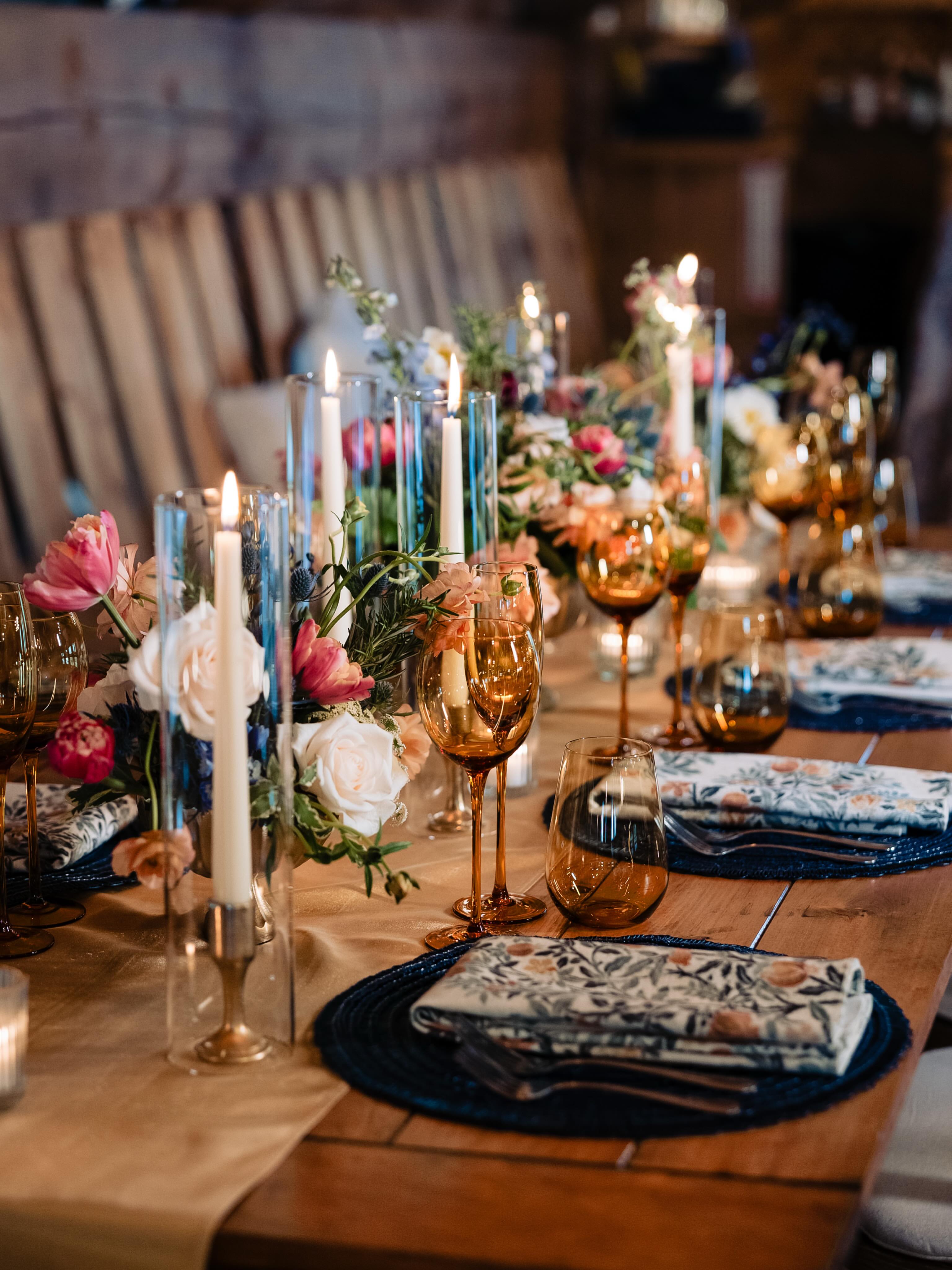 A beautifully set dining table with white tablecloth, cutlery, and fresh greenery in a cozy, well-lit space.