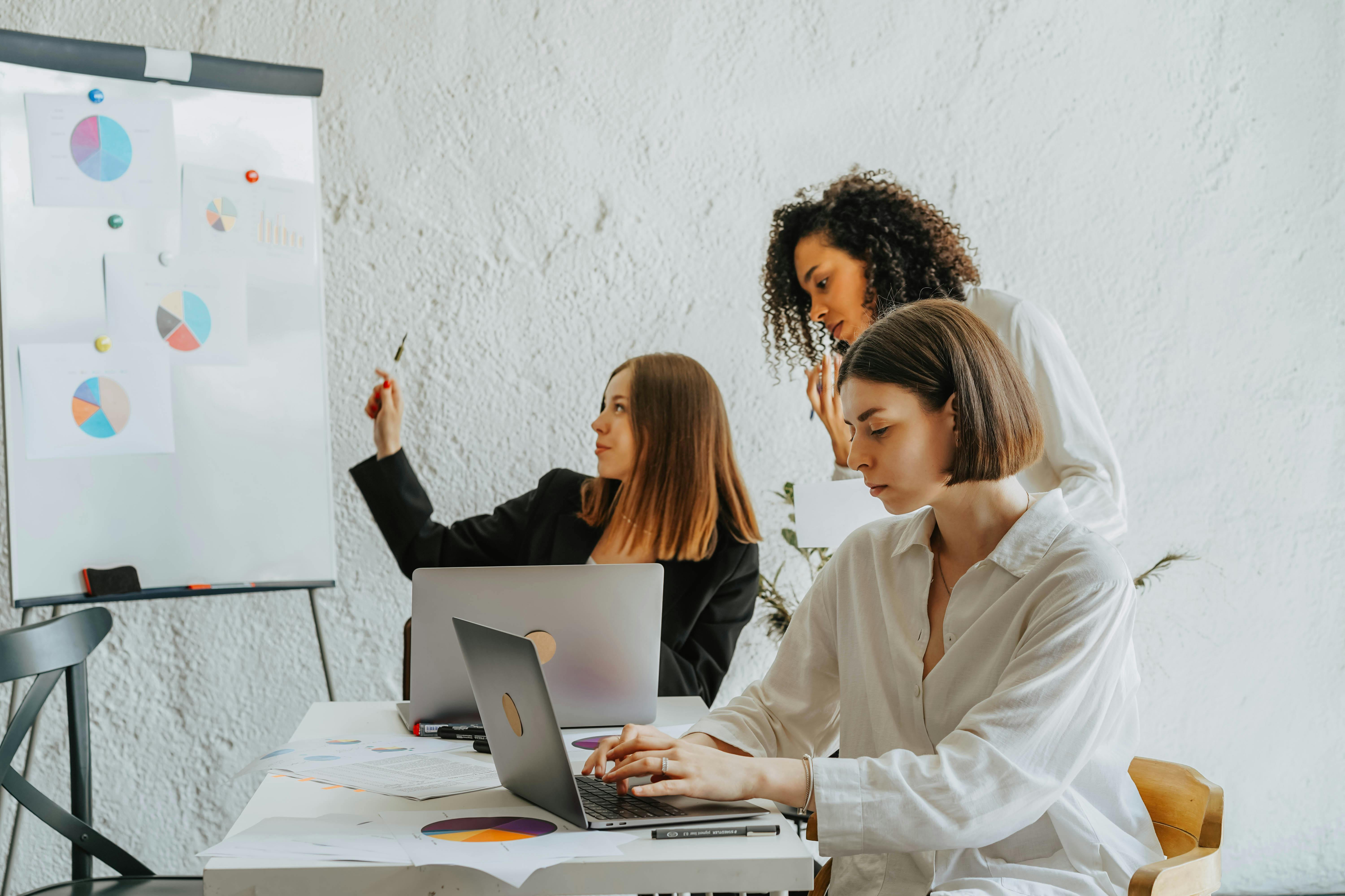 Team analizza grafici su lavagna e laptop: workshop dati, marketing e report operativi