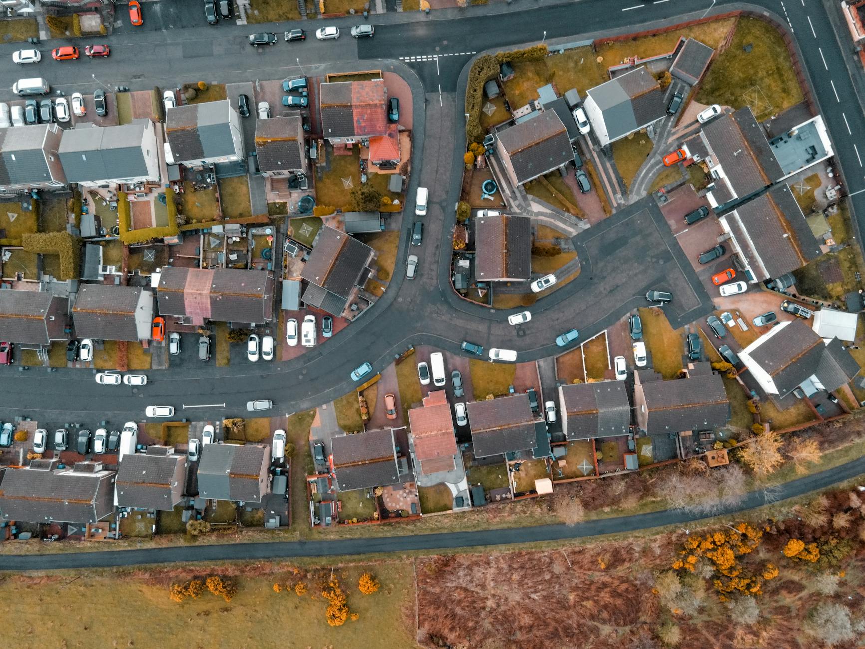 Aerial drone view of a UK residential housing estate showing cul-de-sacs, terrace homes and parked cars