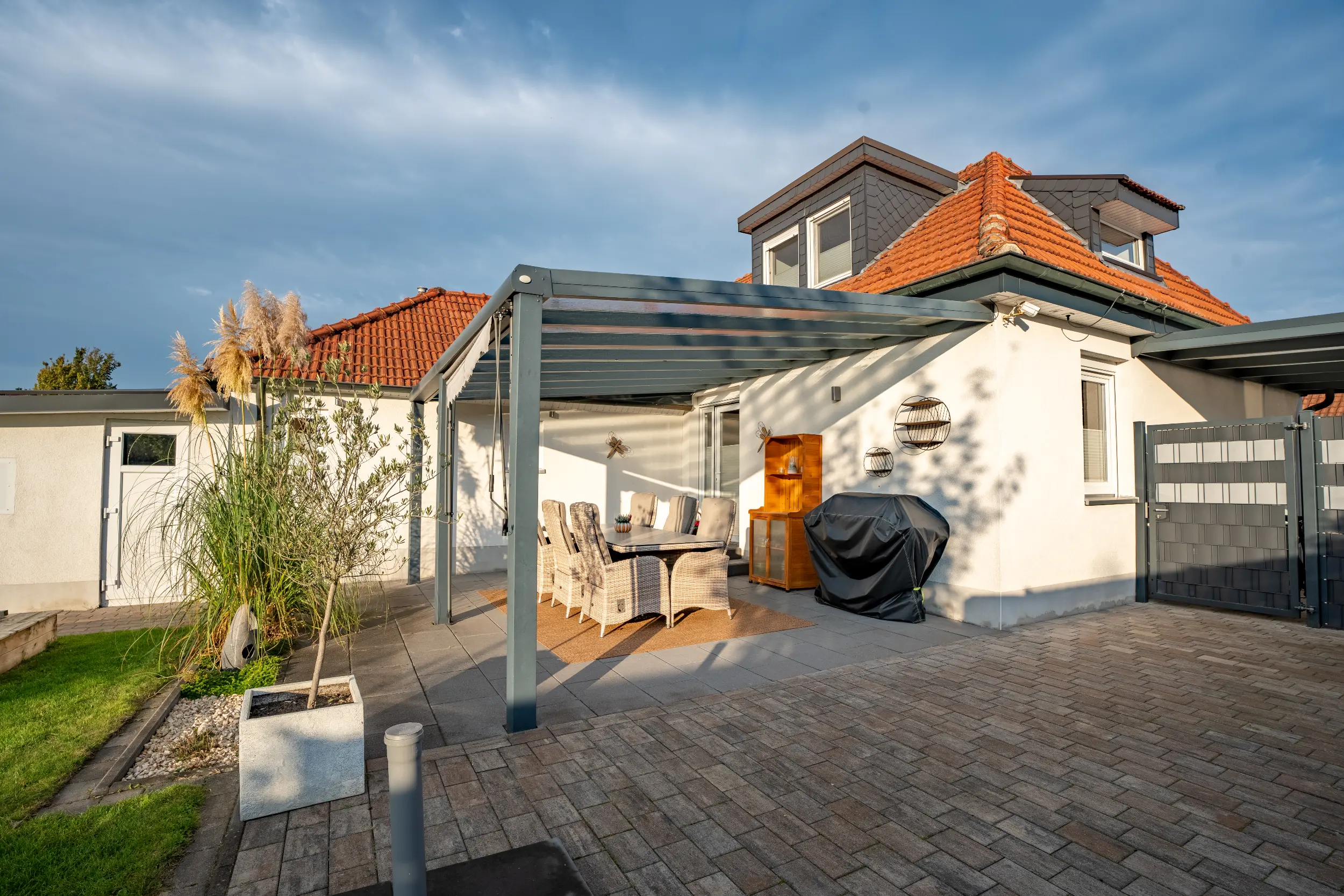 Überdachte Terrasse mit Gartenmöbeln und modernem Eingangsbereich eines Einfamilienhauses in Gronau – Westfalen Wohnen.