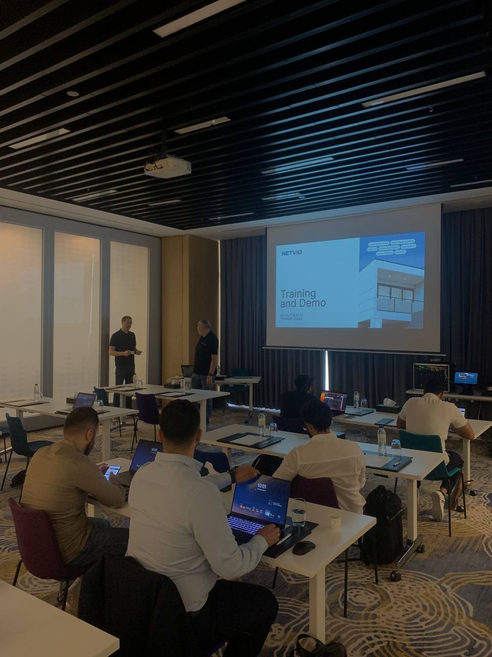 Meeting with projector screen, tables, and attendees