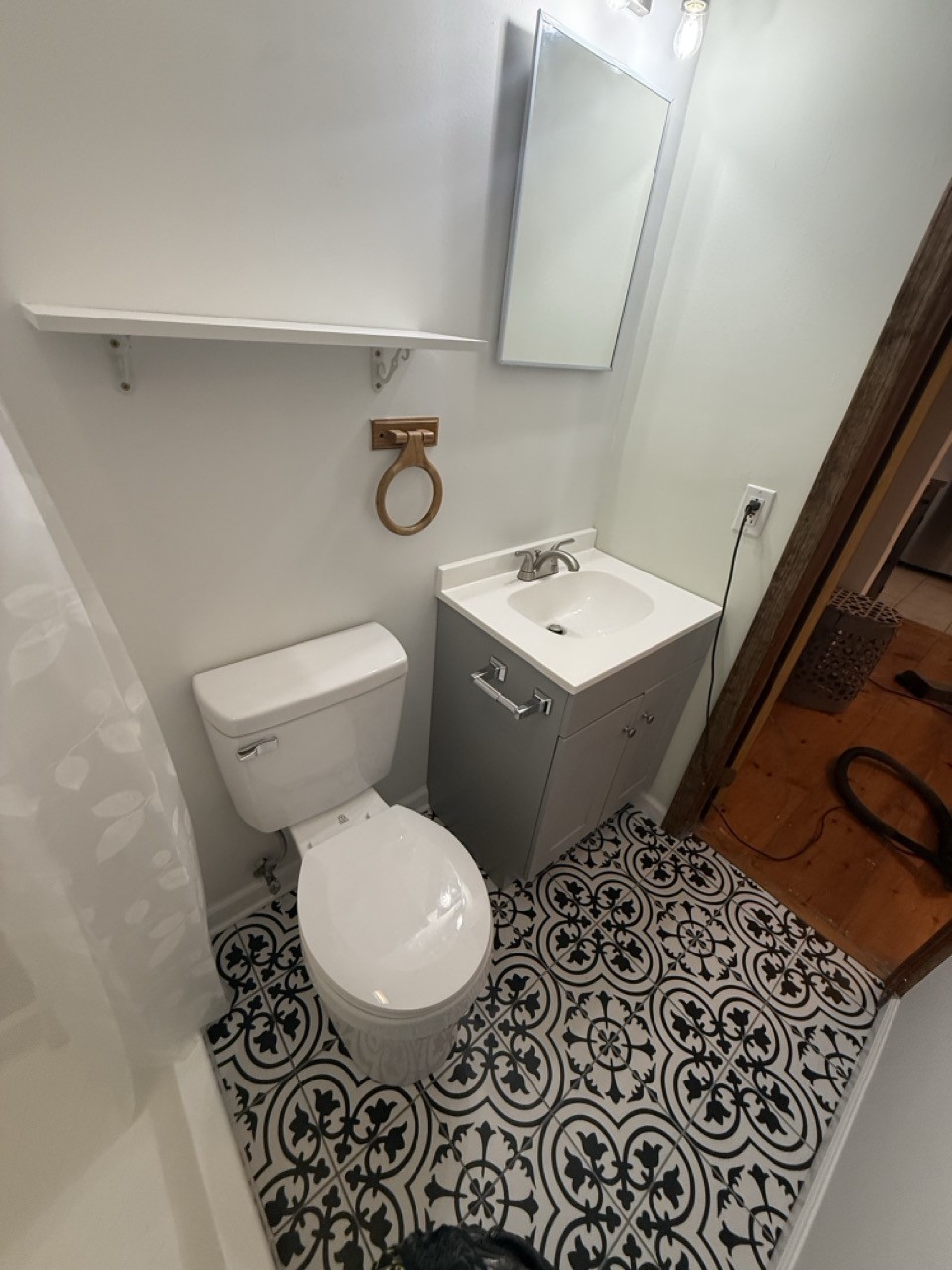 Finished bathroom with a new toilet, gray vanity and patterned tile floor