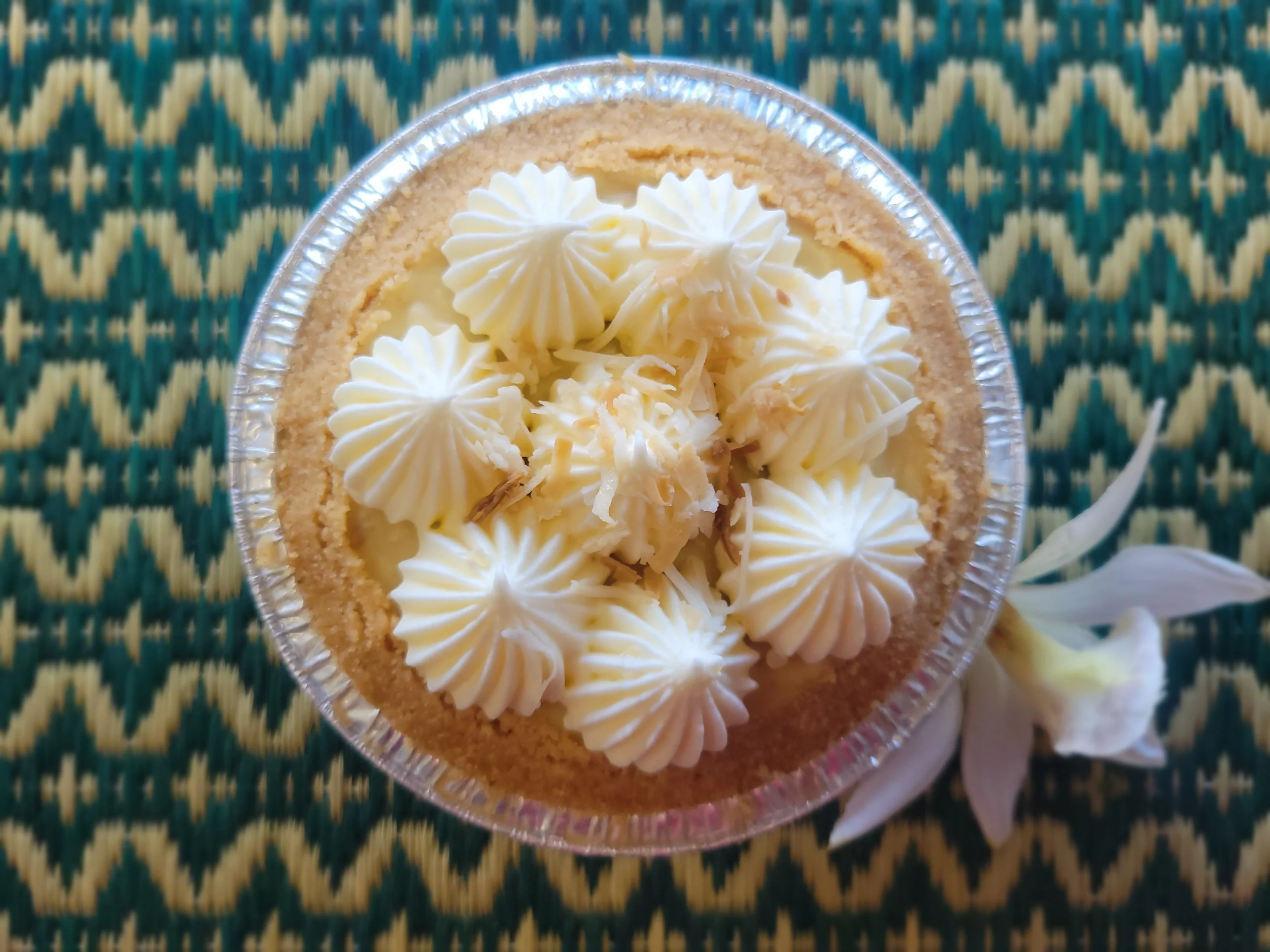 A thick slice of banana cream pie featuring a pale yellow custard layer, fresh banana slices, and a high peak of white whipped cream on a buttery cookie crust.