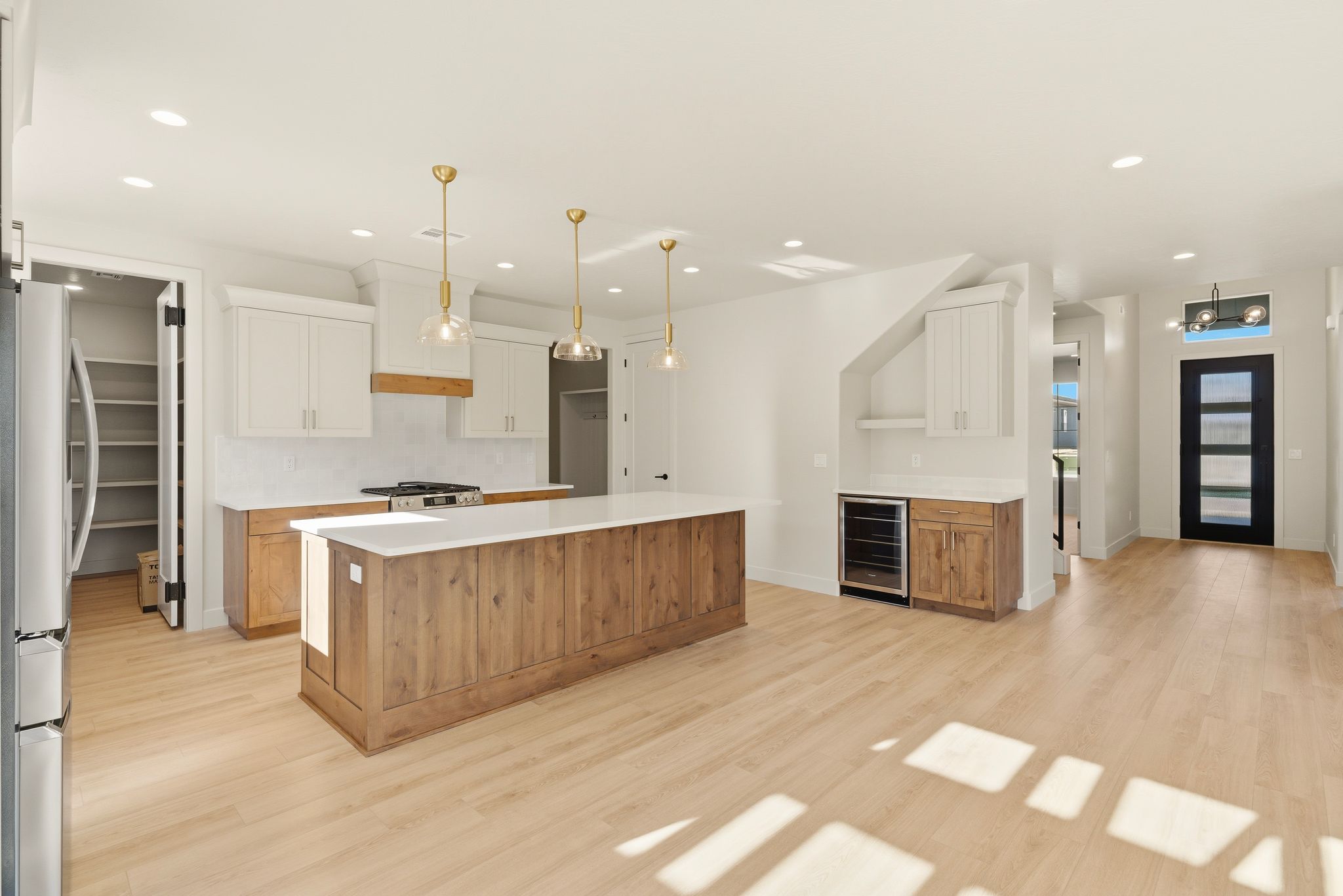 Kitchen at The View at Falcon Ridge in Hurricane, Utah, featuring a mix of wood and white cabinets with gold hardware and ample storage.