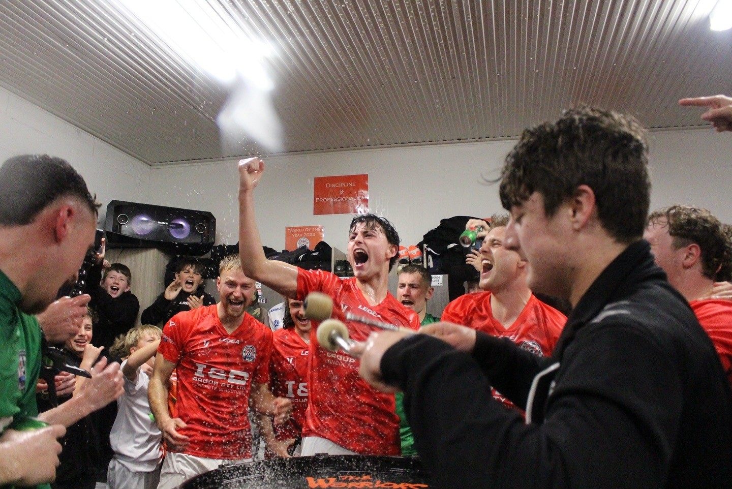 NGWFC senior team celebrating promotion in changerooms with drinks spraying and players cheering