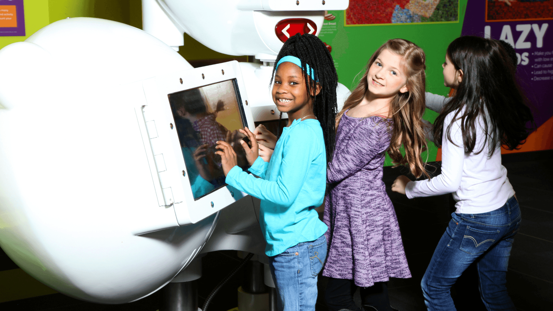 Three girls smile as they pick different snacks on the screen to digitally smash.
